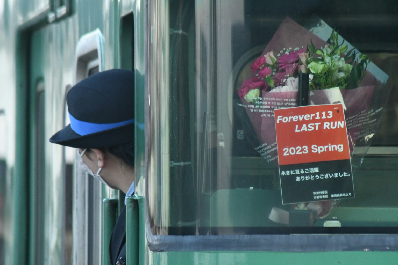 列車員從窗外探出頭,手持花束和標誌