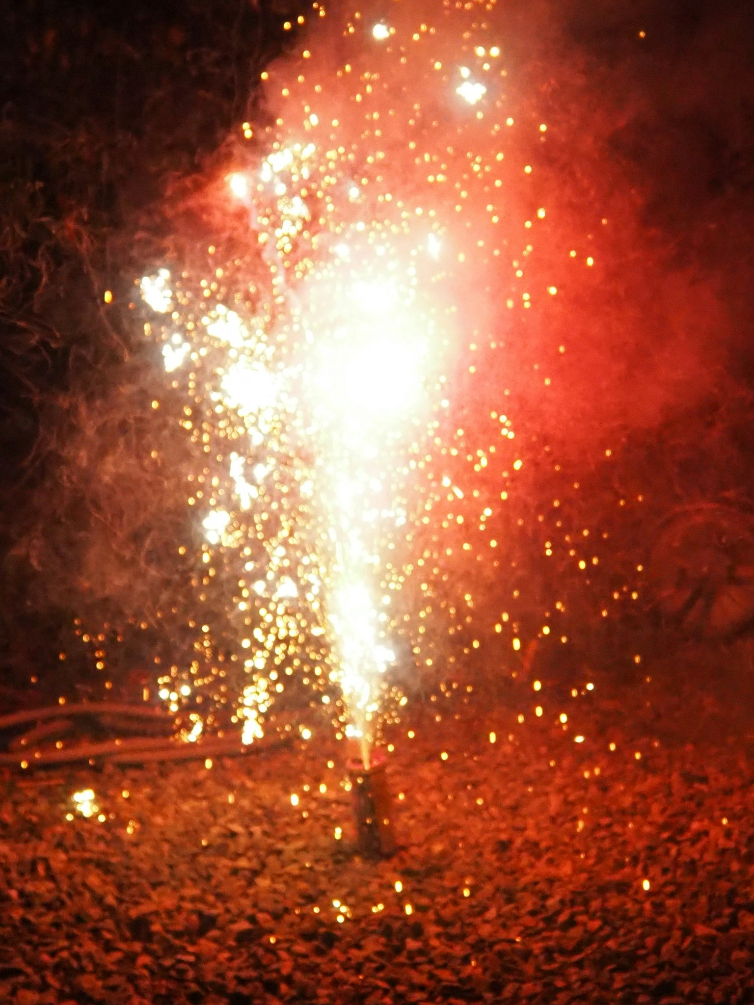 Red fireworks erupting into the night sky with sparks flying