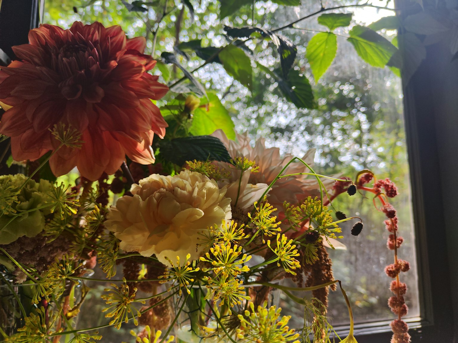 Bunter Blumenstrauß vor grünem Hintergrund durch ein Fenster