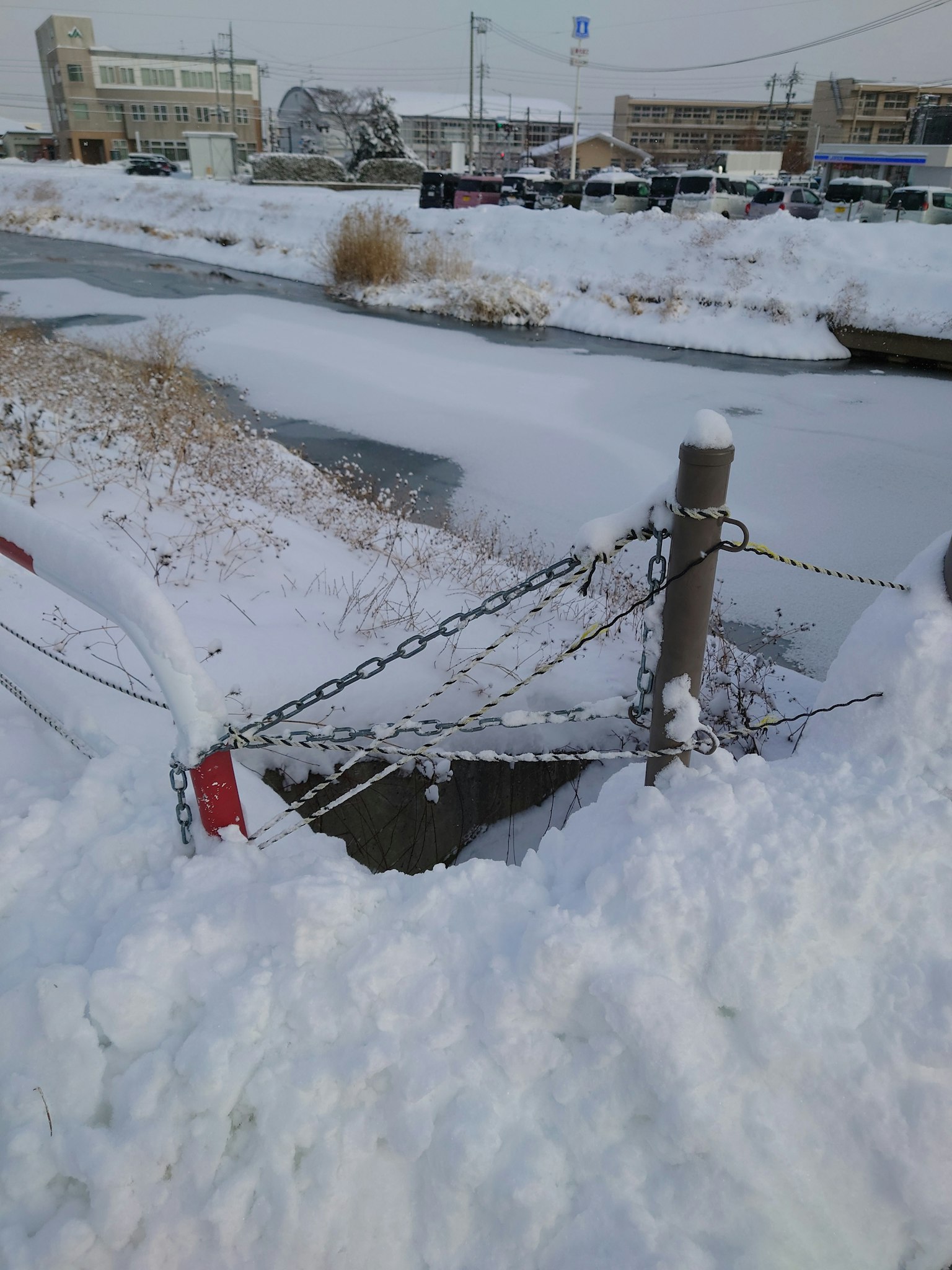 Schneebedecktes Ufer mit einem angeketteten Pfosten