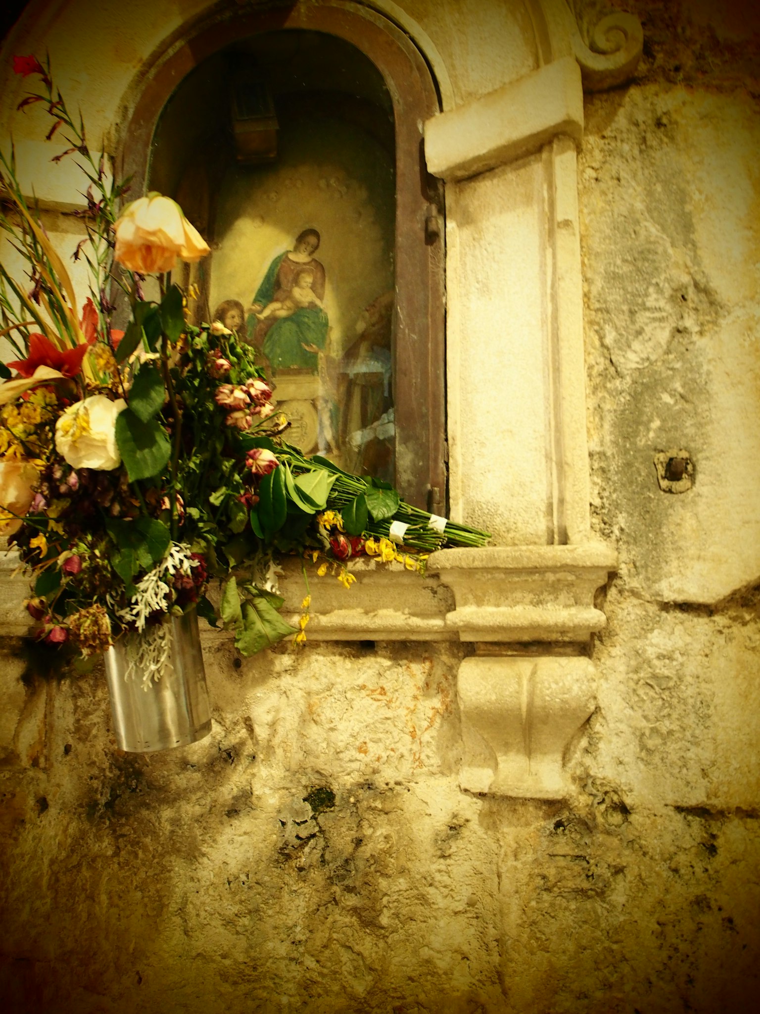 Decorative flowers around a religious painting in a wall alcove