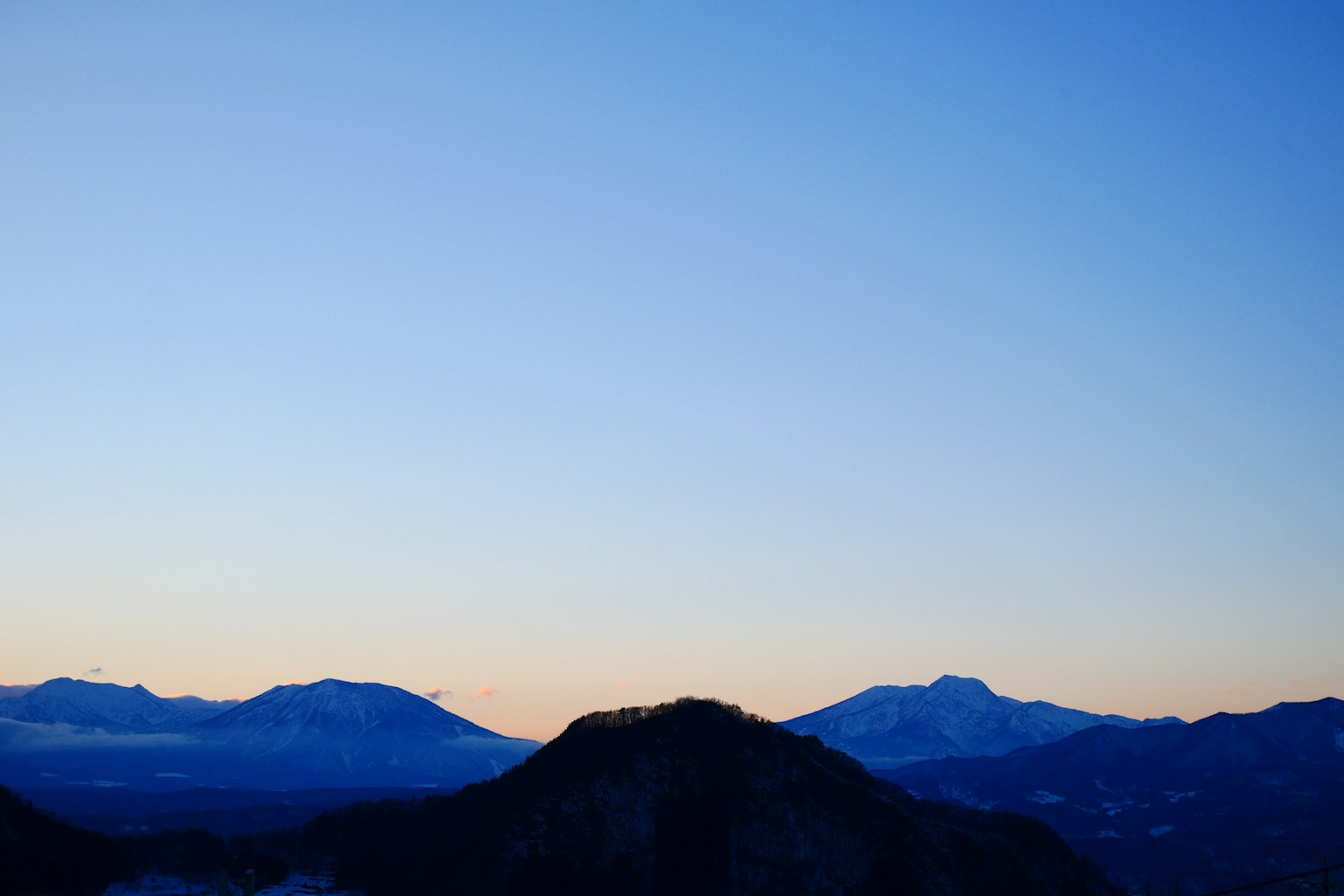 Landschaft mit Bergen vor einem blauen Himmel und schönen Sonnenuntergangstönen