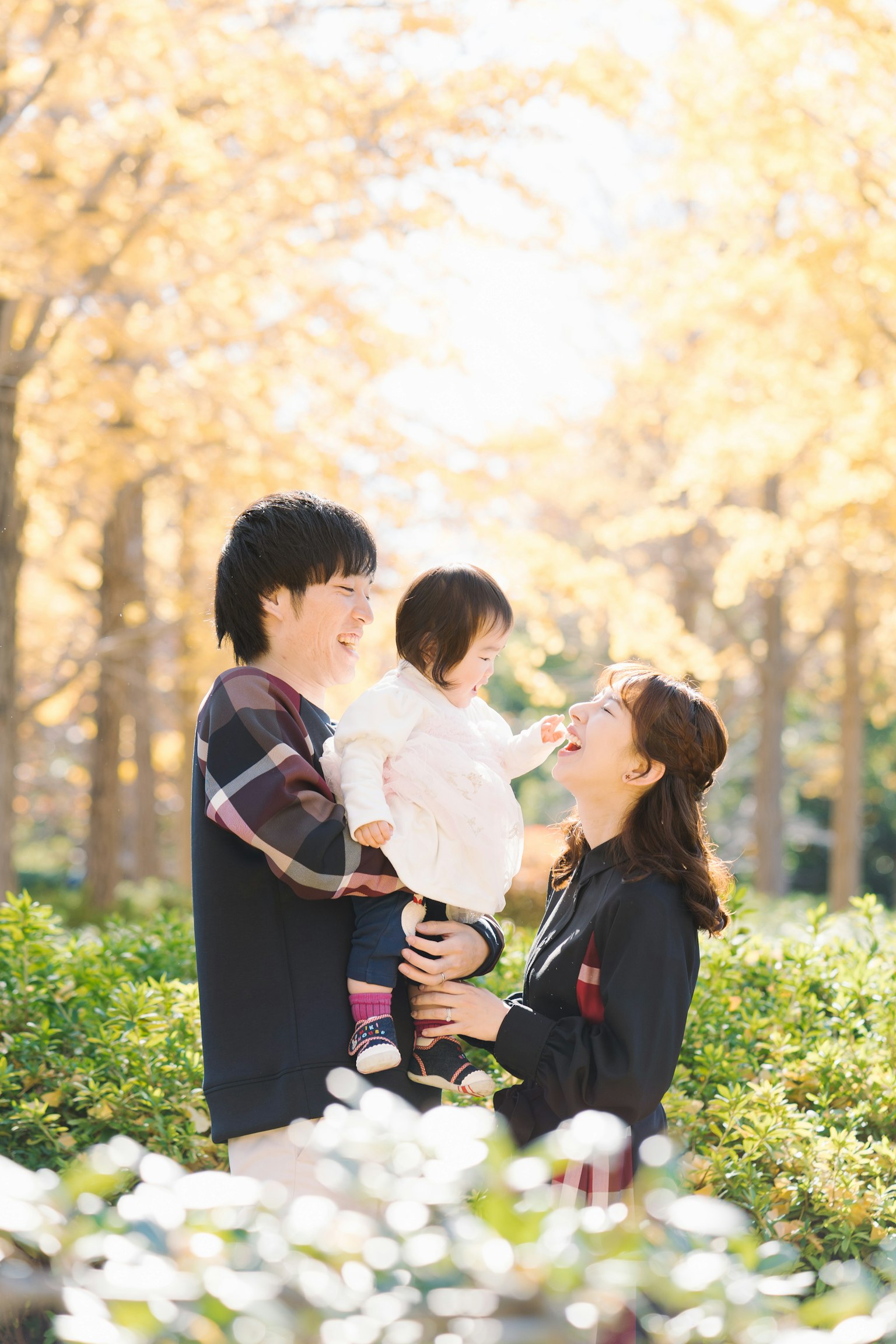 Familie, die gemeinsam in einem Herbstpark mit goldenen Blättern Spaß hat