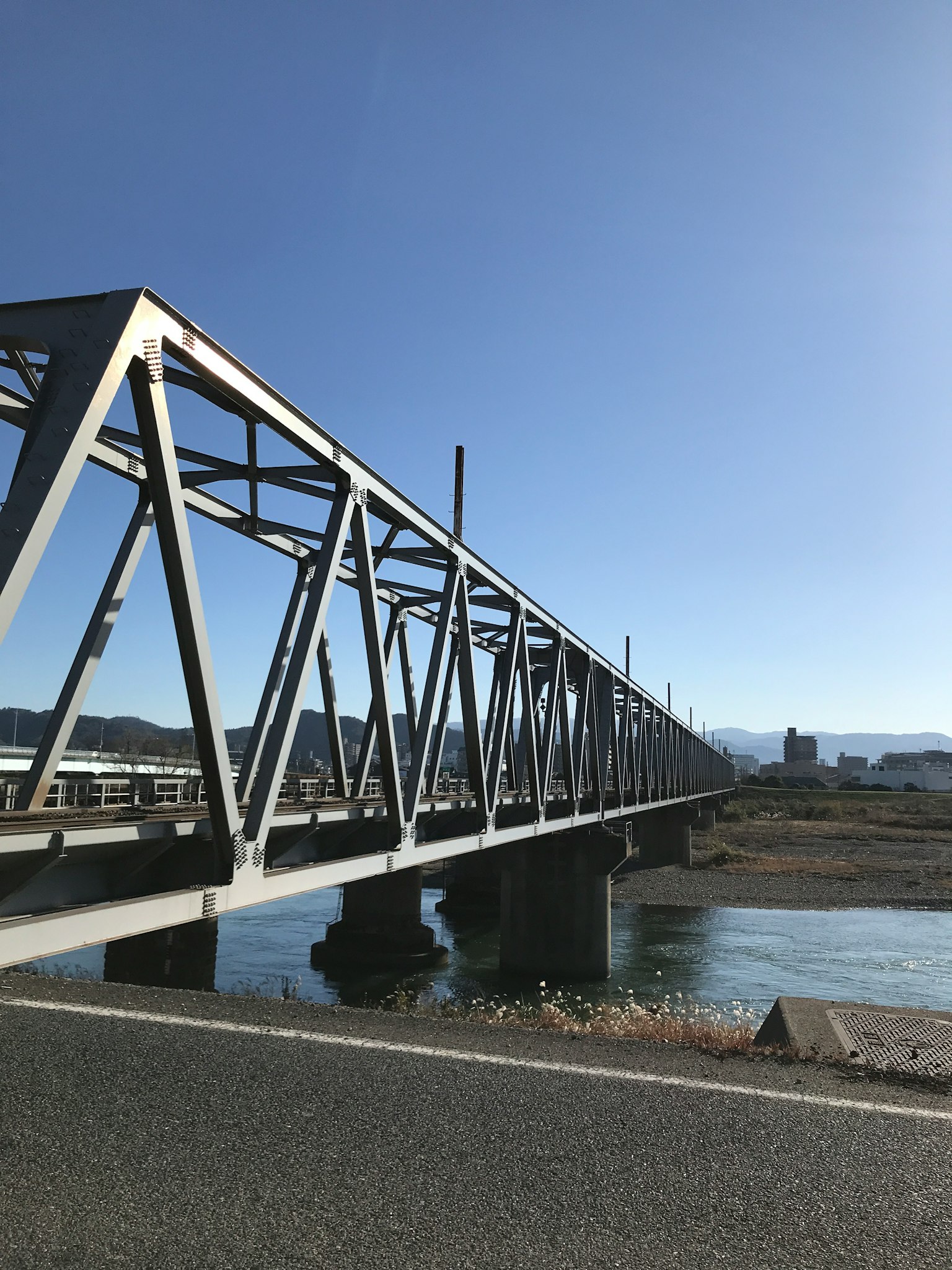 Stahlbrücke über einen Fluss unter einem hellblauen Himmel