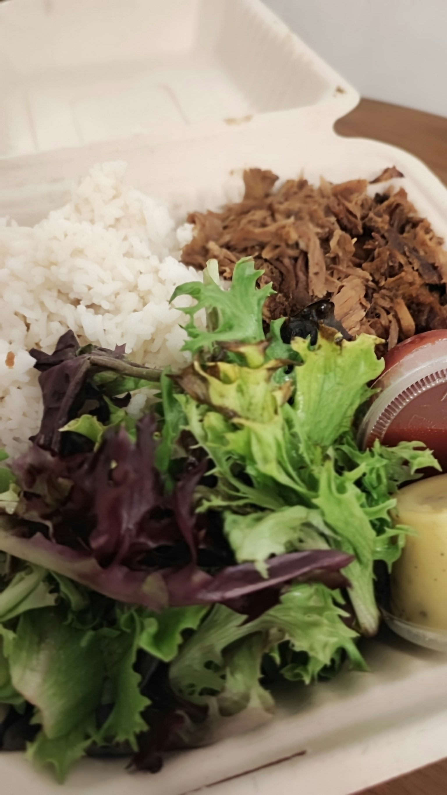 Kotak makanan bawa pulang berisi nasi, salad, dan hidangan daging