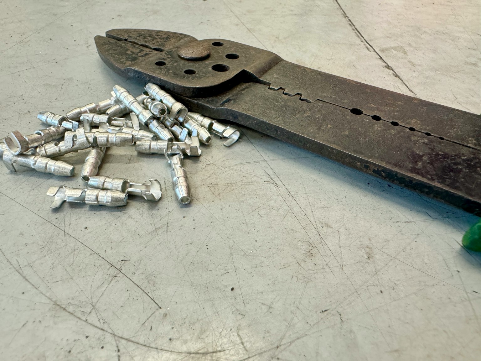 Un vecchio paio di pinze accanto a pezzi metallici sparsi