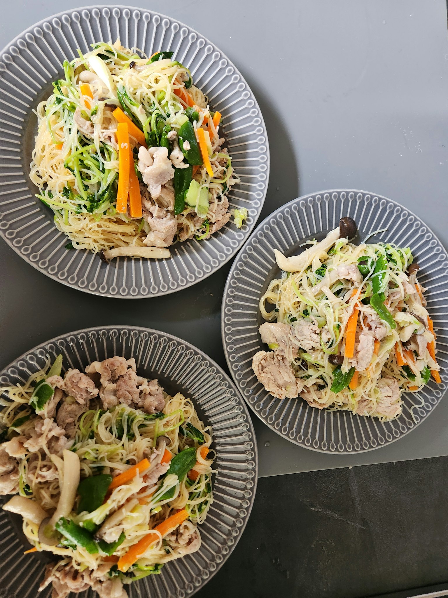Tre piatti di pasta con verdure e carne