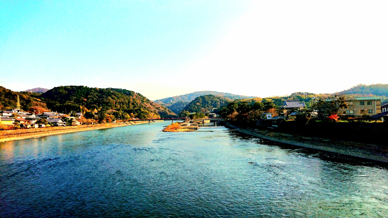 Vue pittoresque d'une rivière calme entourée de collines et de maisons