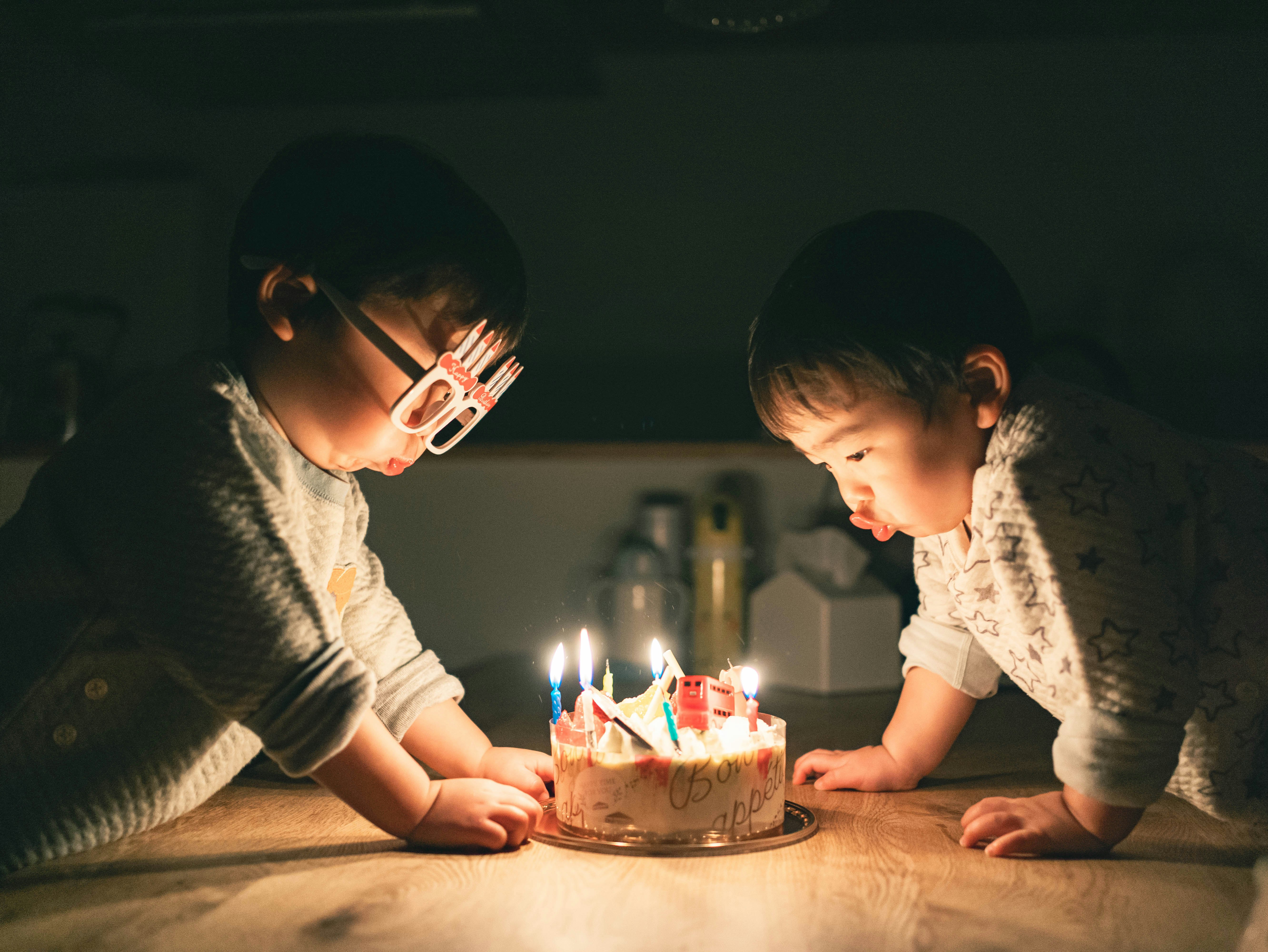 ろうそくの立つケーキを前にした兄弟の誕生日パーティー