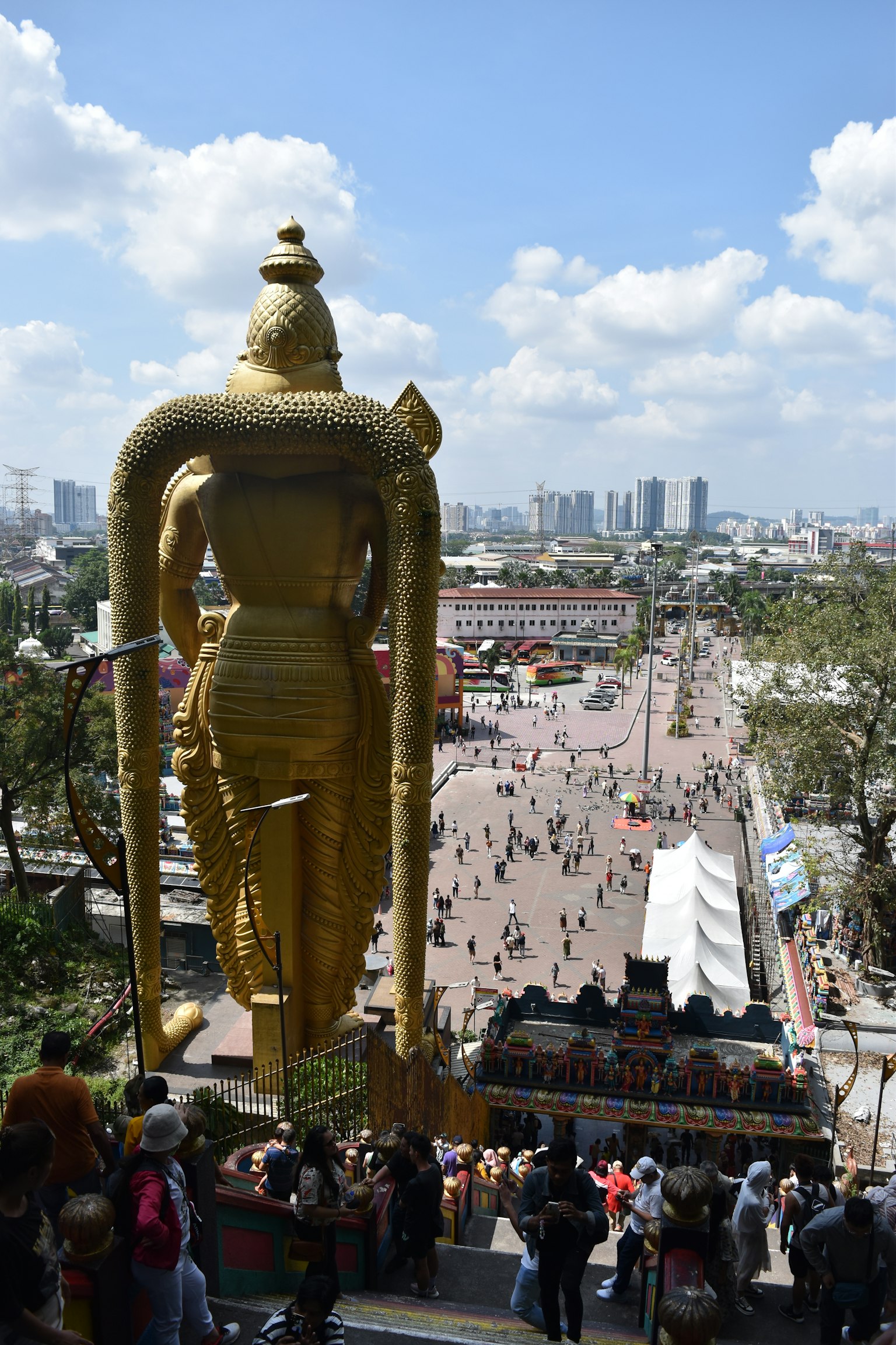 Grande statua di Buddha dorato che sovrasta una scena cittadina vivace