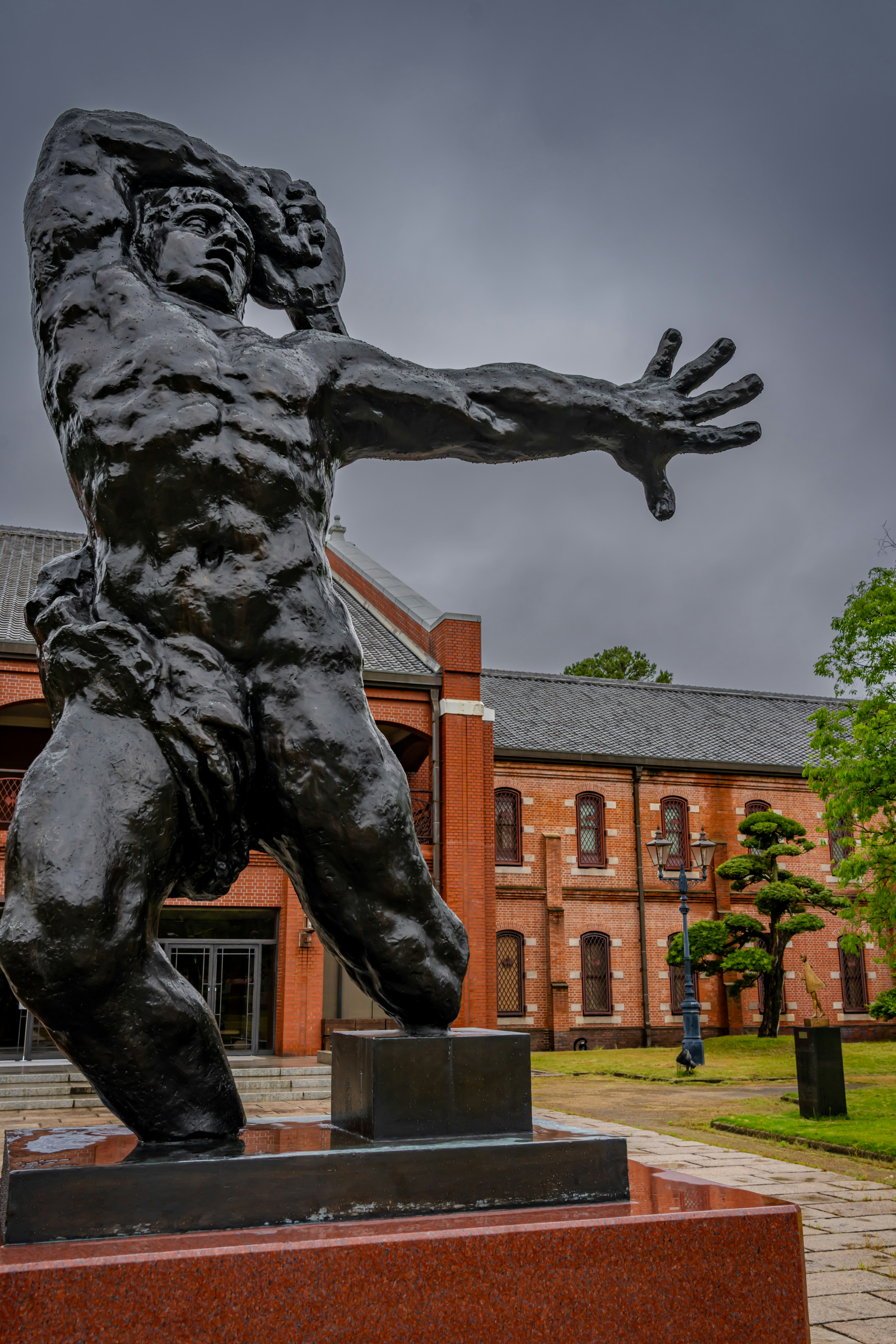 statue en bronze dans une cour avec un bâtiment en briques