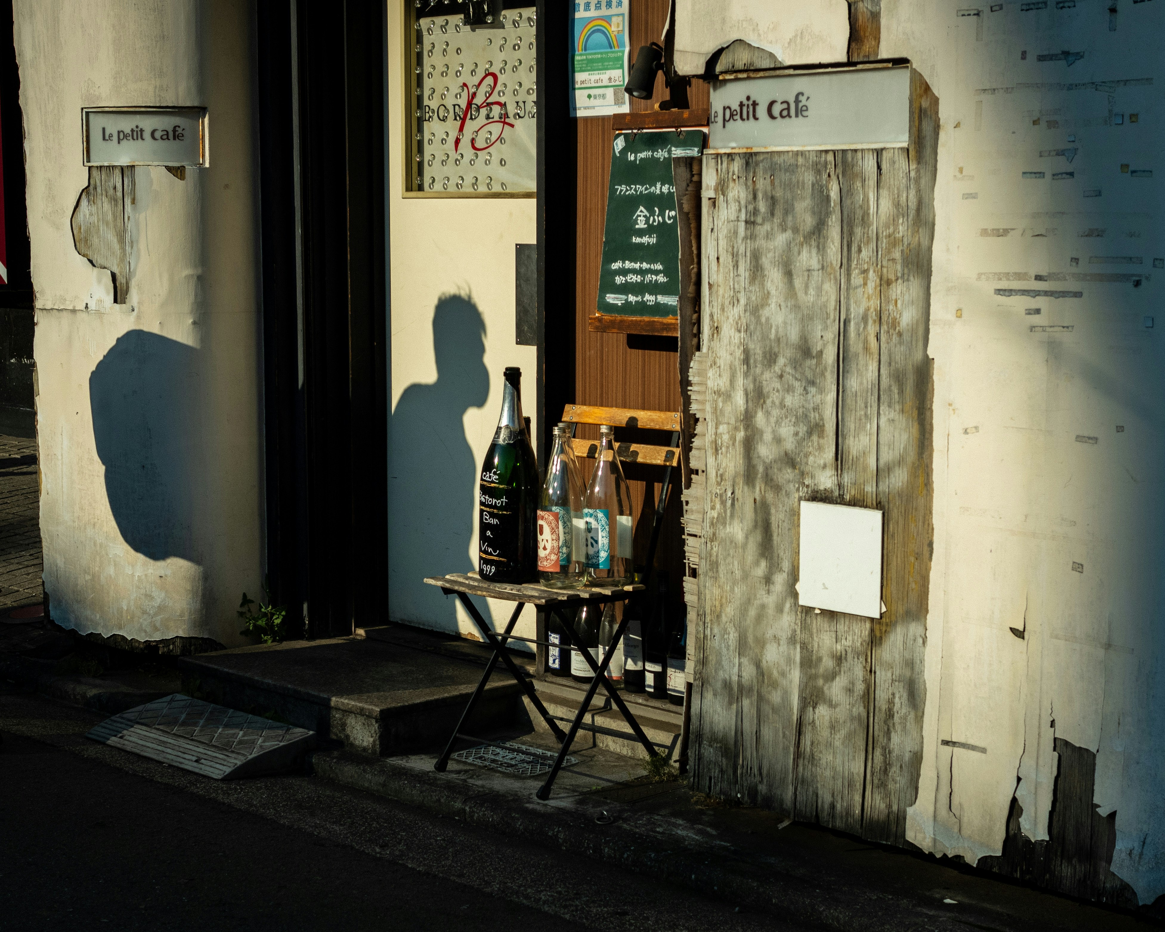 瓶が並ぶ小さな店先の路地のカフェ