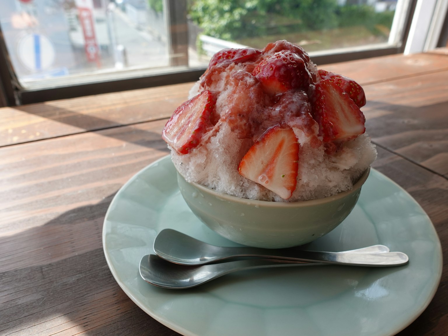 Cuenco de hielo raspado cubierto con fresas sobre una mesa de madera