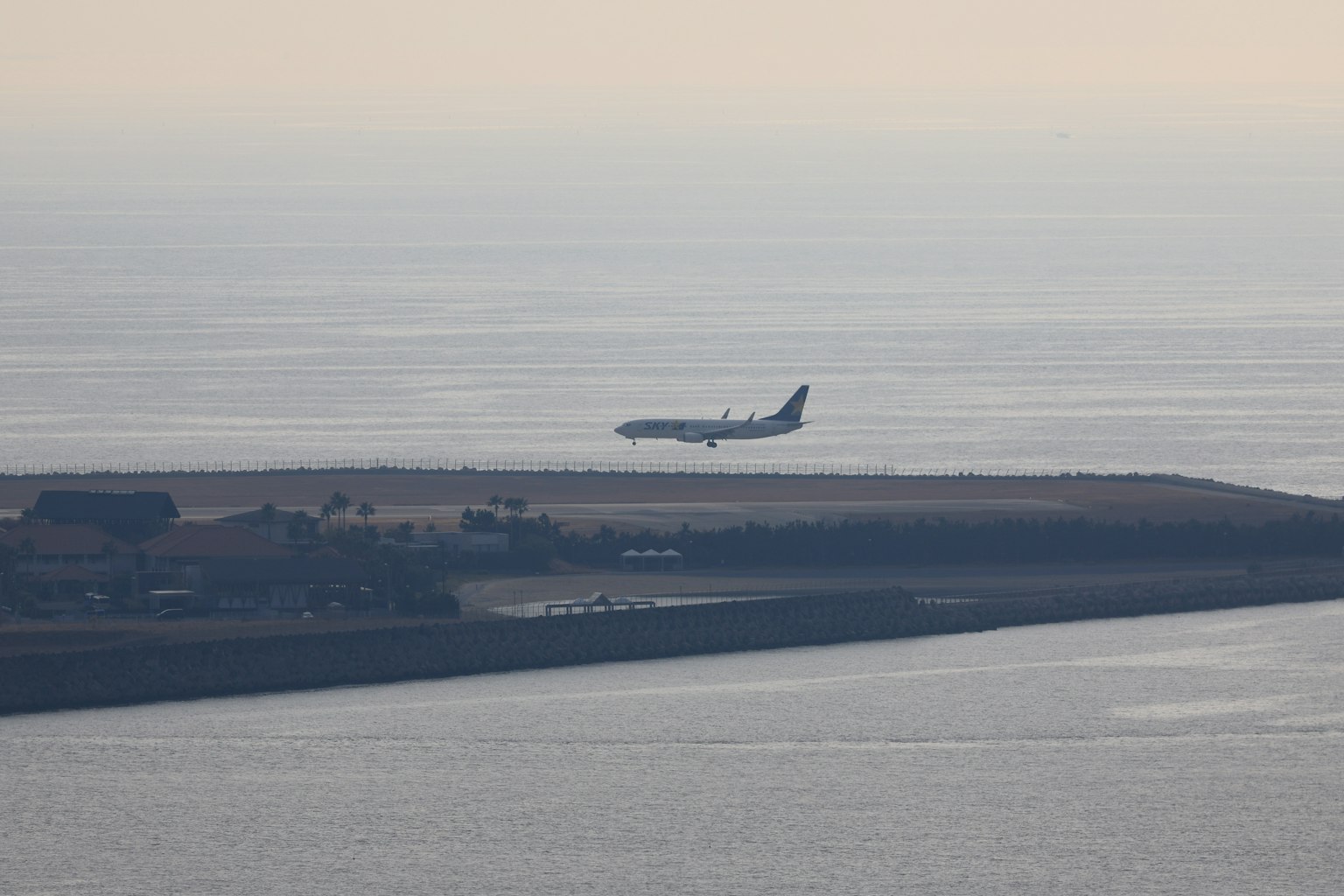 Aereo in atterraggio sopra l'oceano con paesaggio circostante