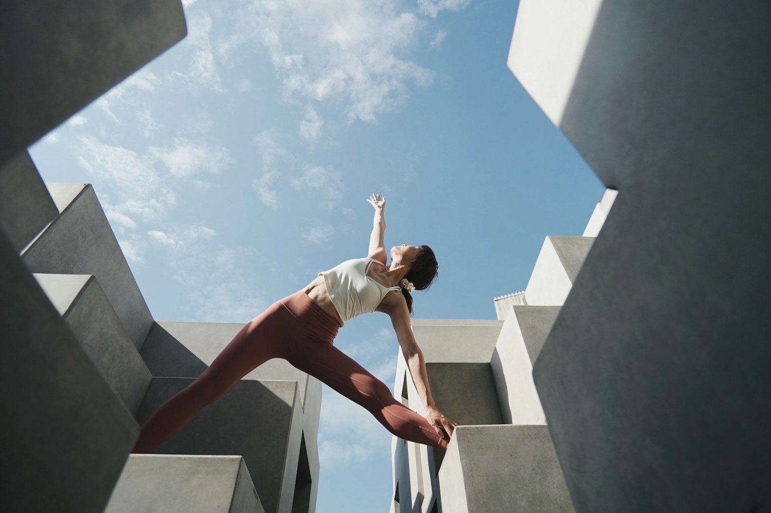 青空の下でポーズをとる女性のダンスパフォーマンス 周囲はコンクリートの構造物