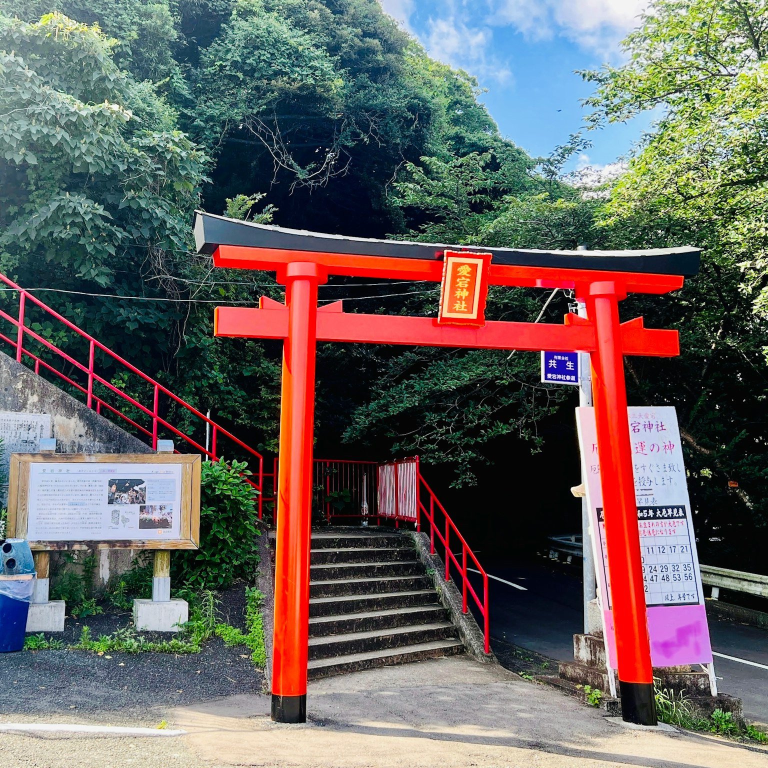 Eingang eines Schreins mit einem roten Torii und Treppen, umgeben von üppigem Grün