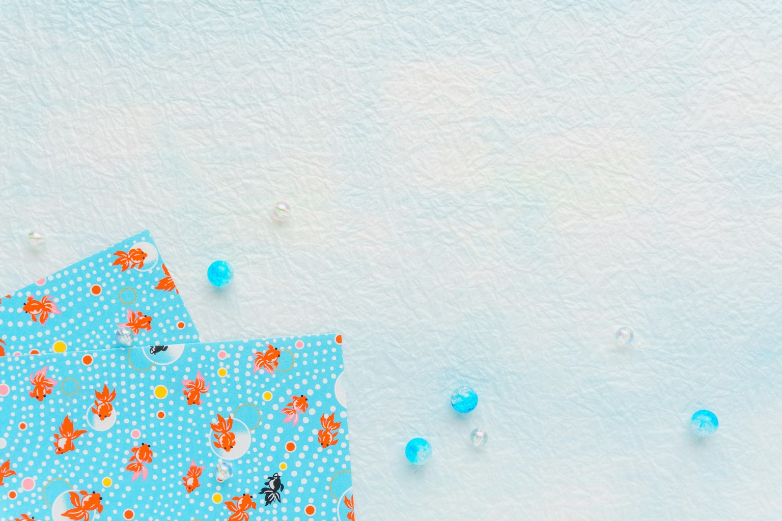 Fondo azul con tela de patrón floral rojo y cuentas transparentes dispuestas