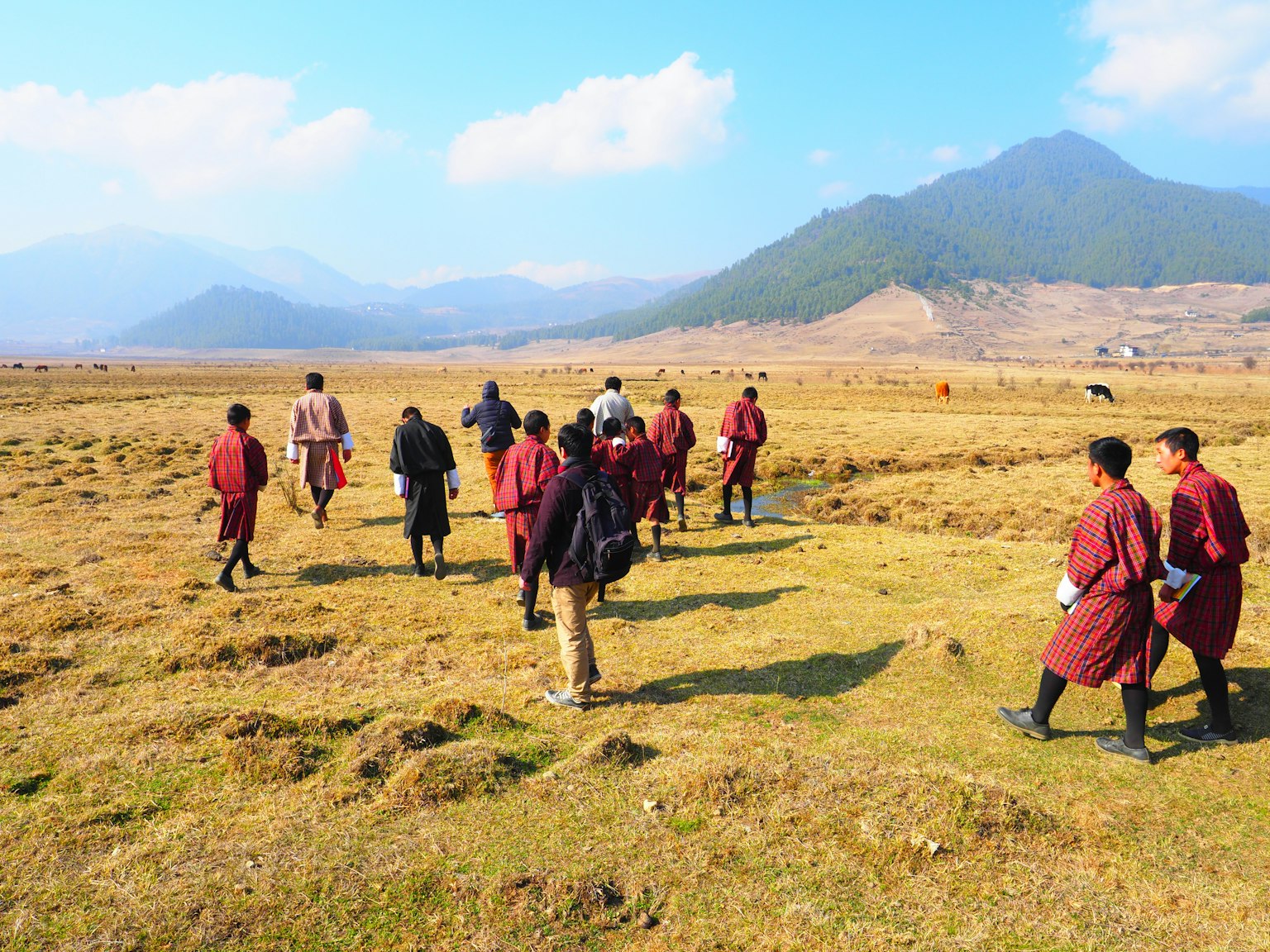 Gruppo di persone che camminano in un vasto prato bhutanese