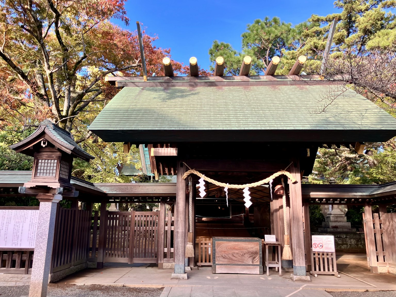 神社的入口，绿色屋顶，周围被秋天的树叶环绕