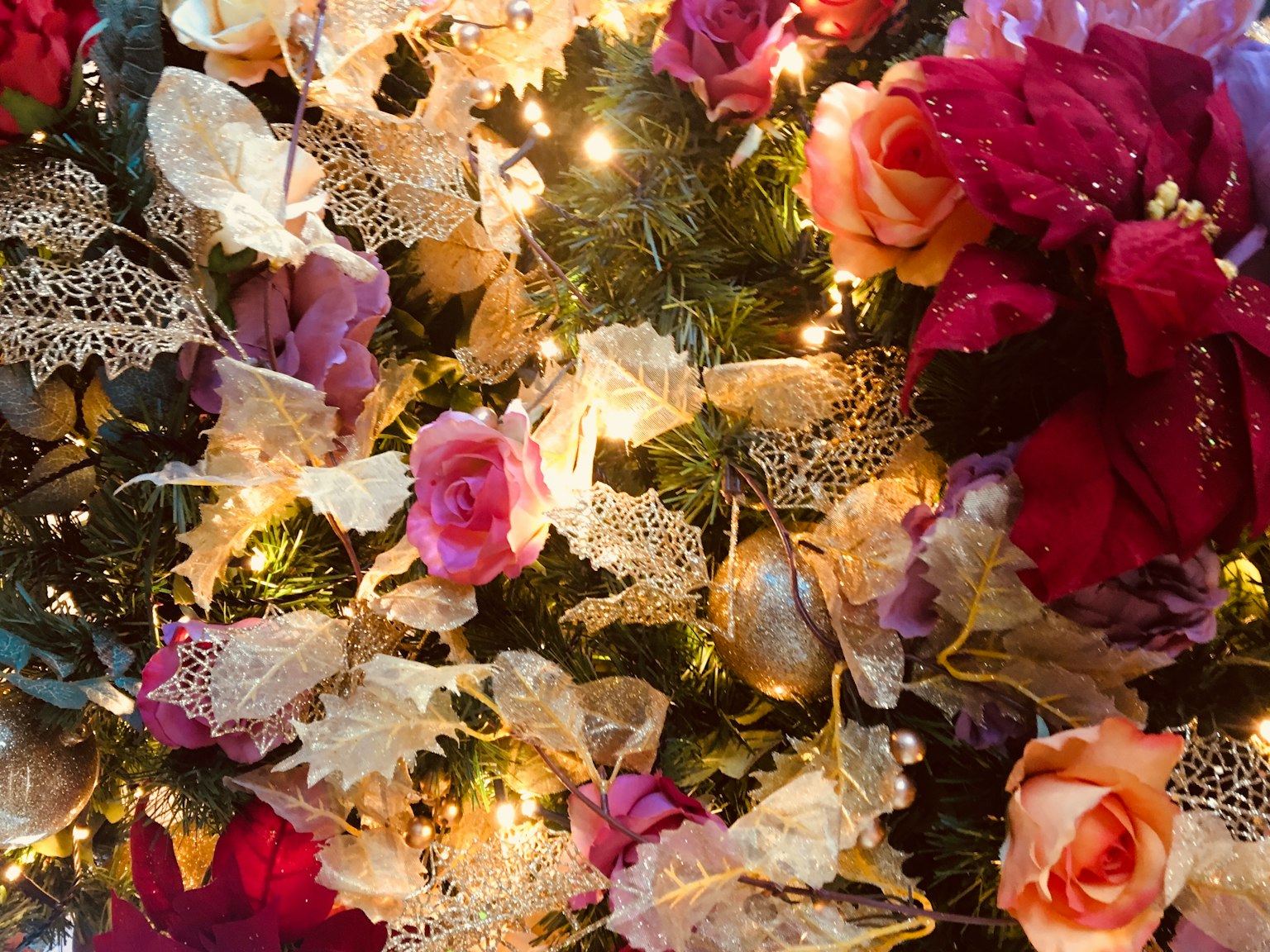 Composición decorativa de flores coloridas y luces en un árbol de Navidad