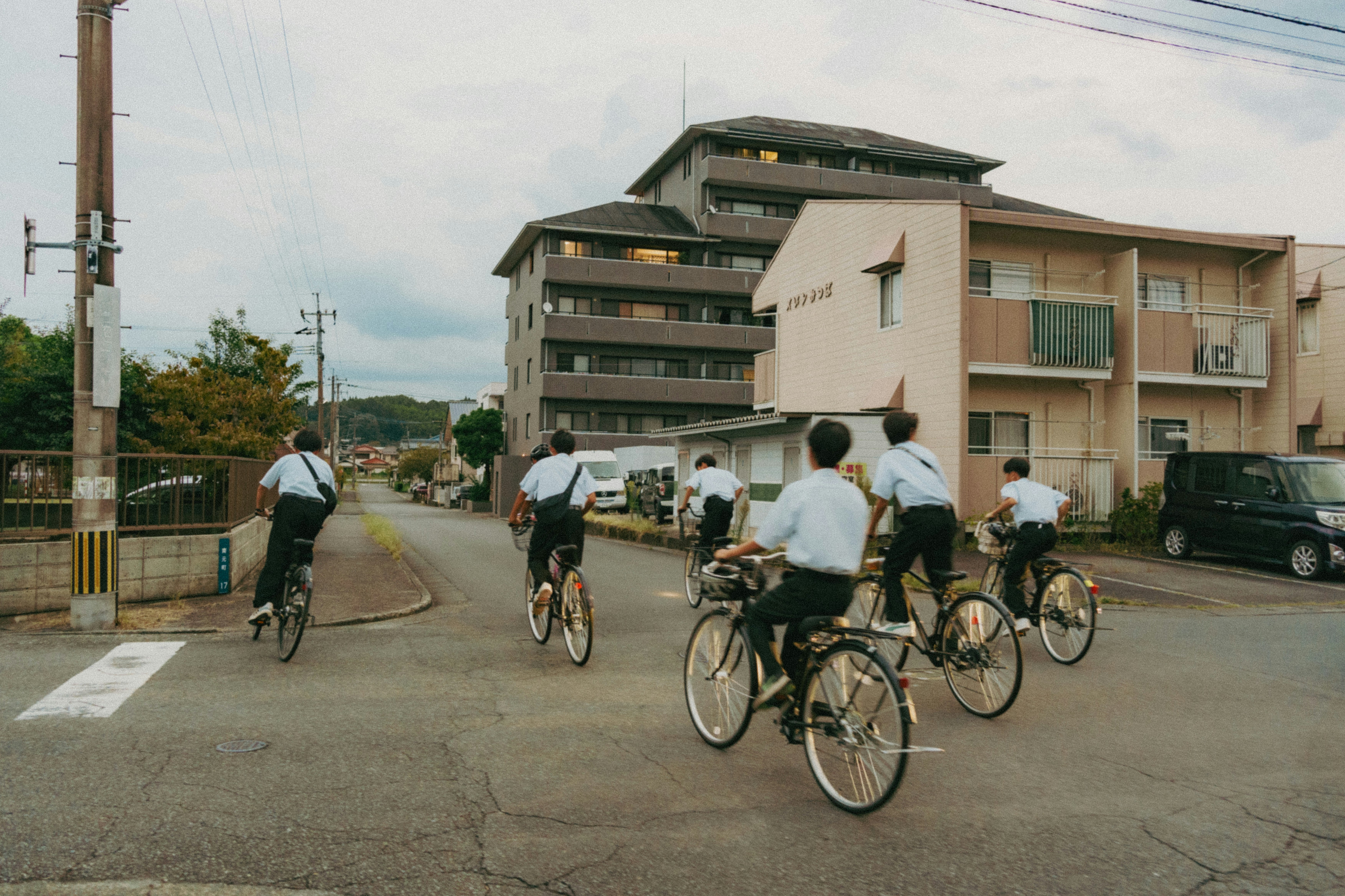 自転車に乗る人々が並ぶ郊外の道路風景