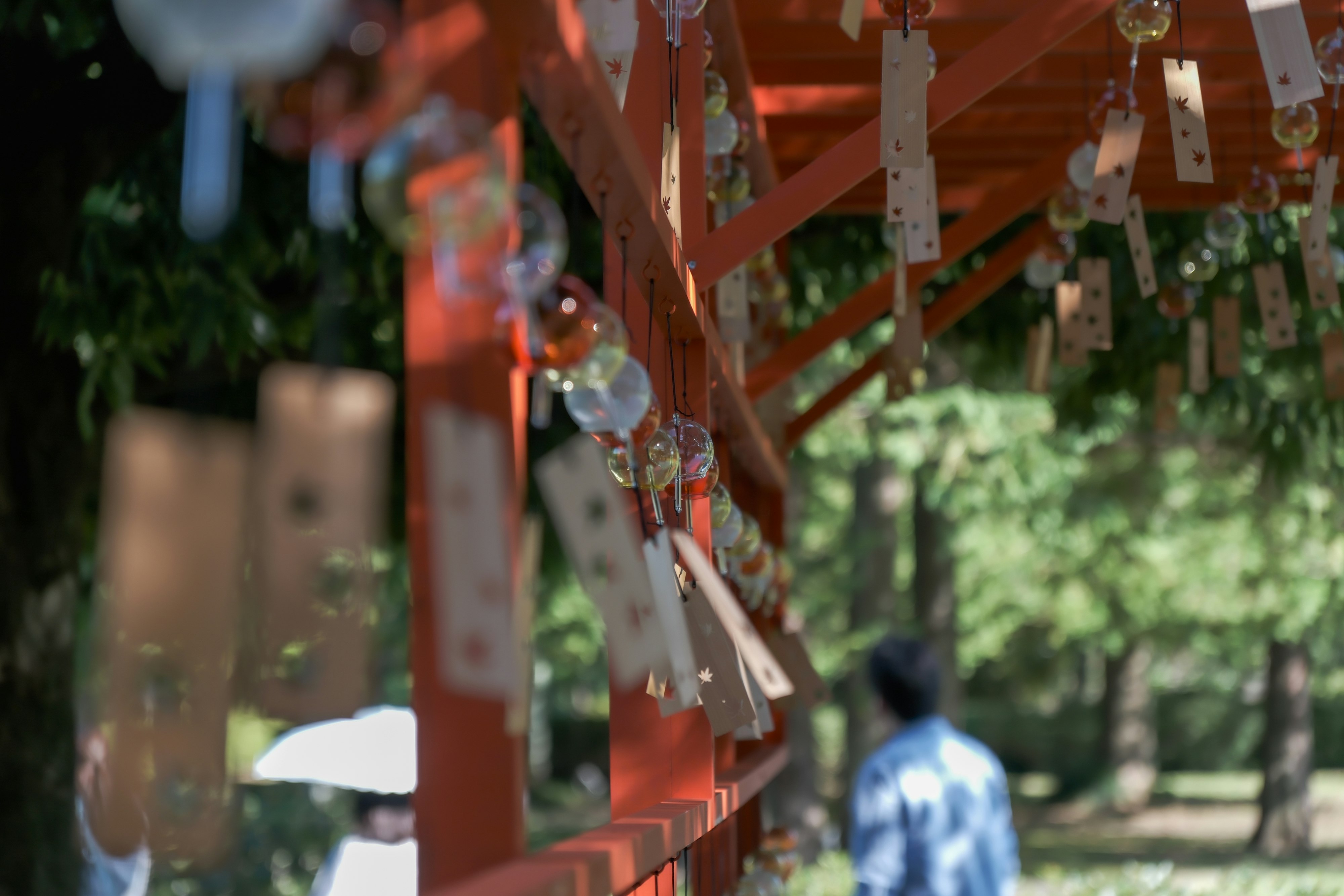 红色鸟居旁的绘马与风铃陈列在神社小路上