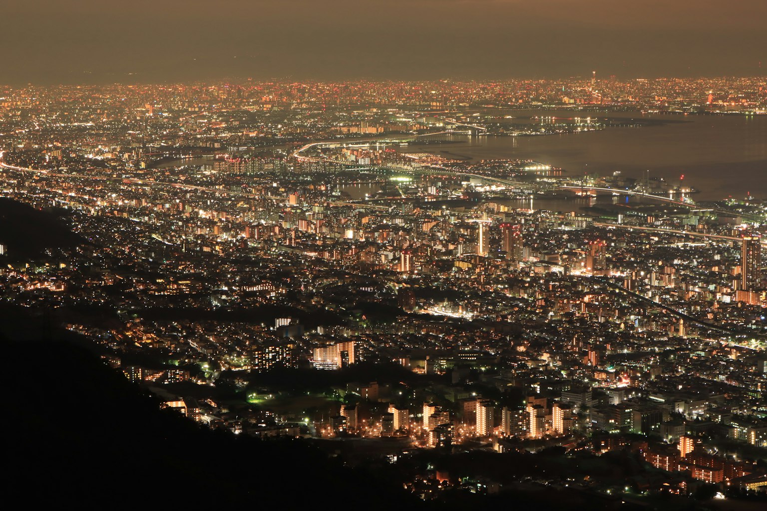 Panoramablick auf eine Stadt bei Nacht mit einem Lichtermeer und verstreuten Gebäuden