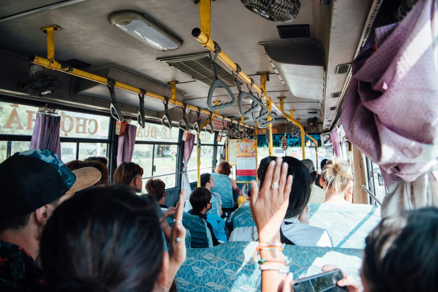 Interior of a bus with passengers raising hands
