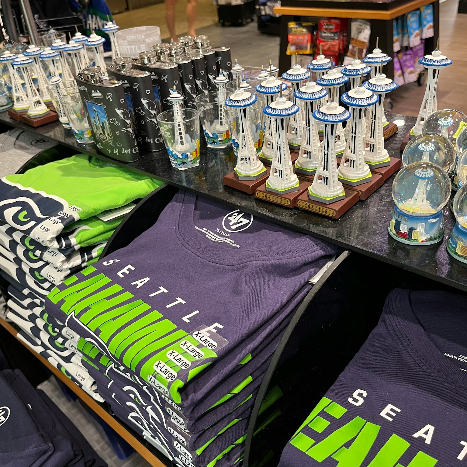 Pemandangan dalam toko suvenir dengan barang bertema Seattle termasuk kaos dan miniatur landmark
