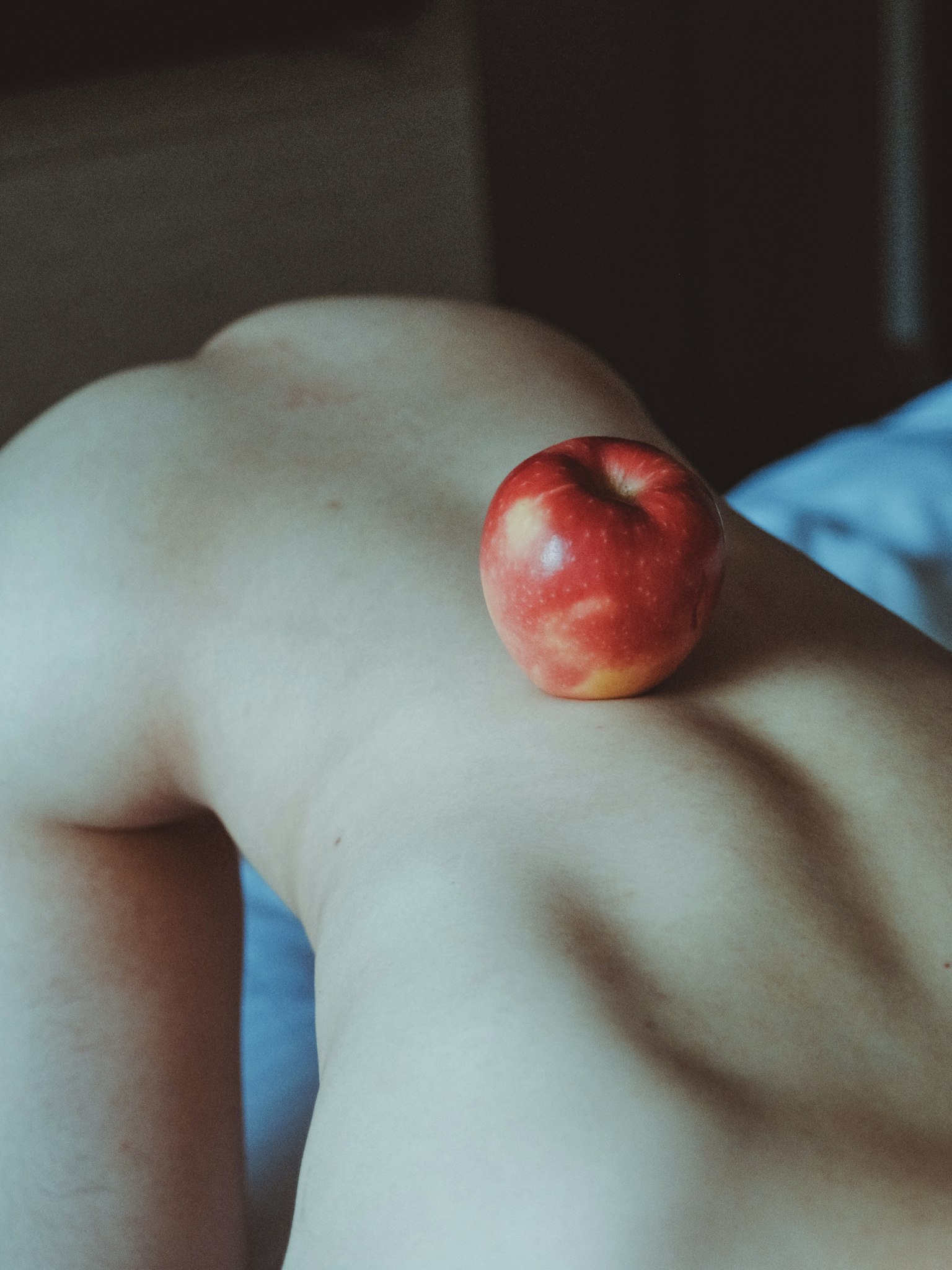 肌の上に置かれた赤いリンゴのある背中の写真