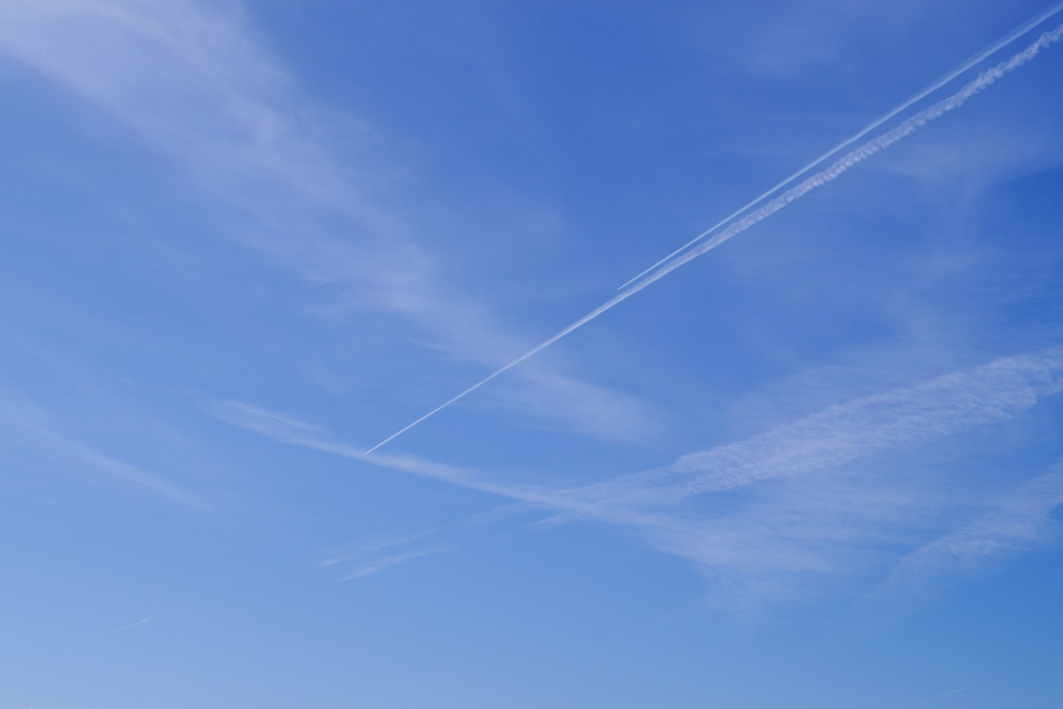 Blauer Himmel mit sich kreuzenden weißen Kondensstreifen