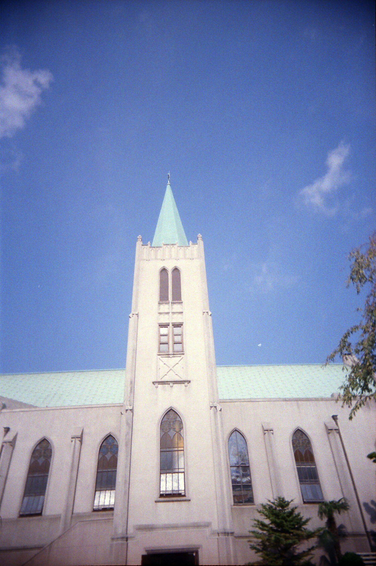 Tour d'église blanche avec une flèche verte sous un ciel bleu