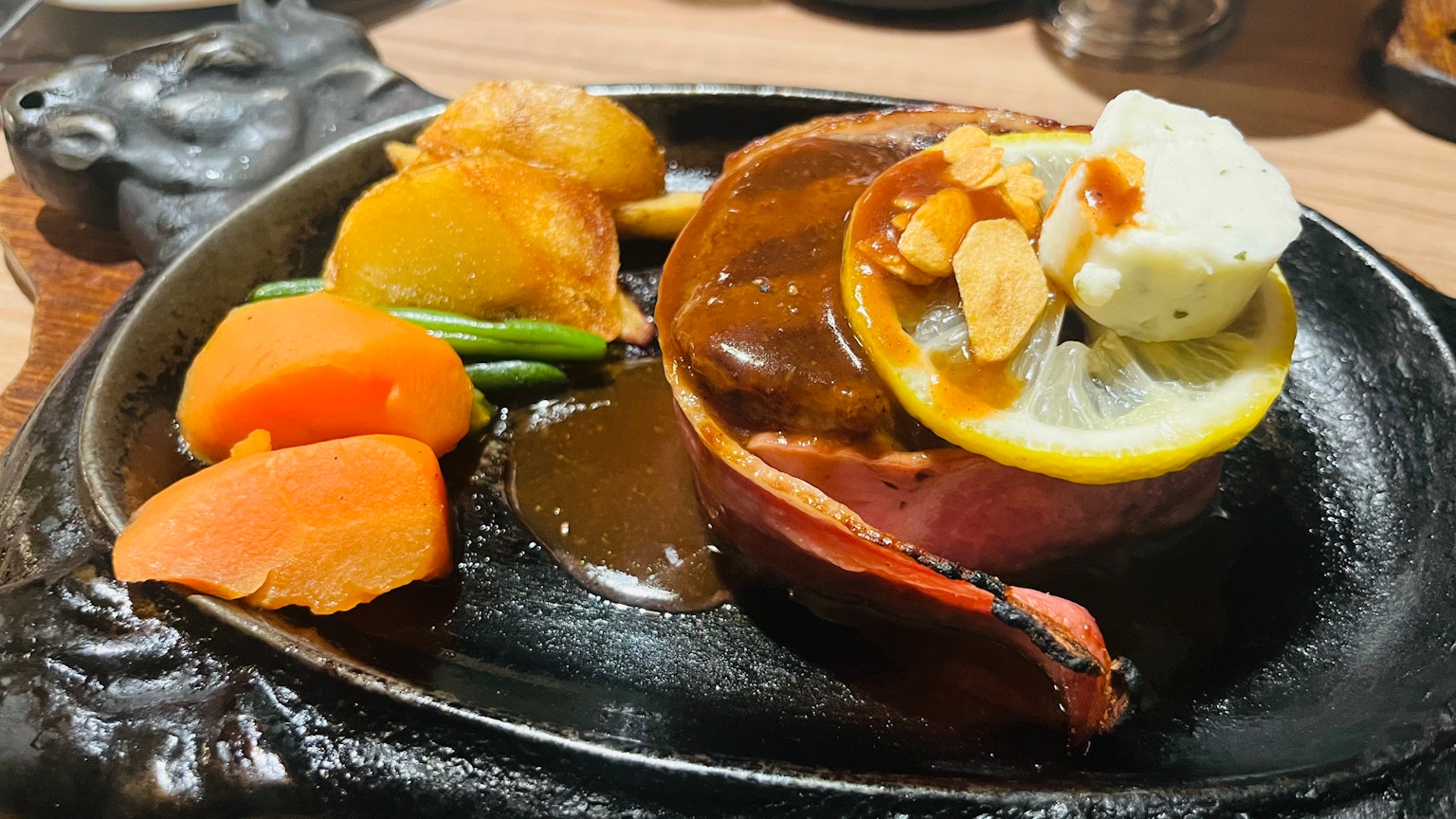 Sizzlendes Fleischgericht mit Sauce und bunten Gemüsebeilagen
