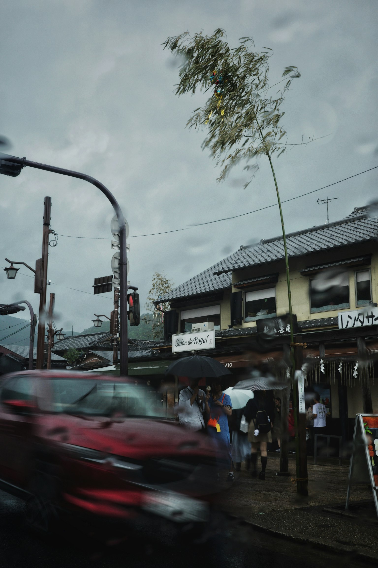 비 오는 날의 도시 풍경과 지나가는 차와 우산을 쓴 사람들