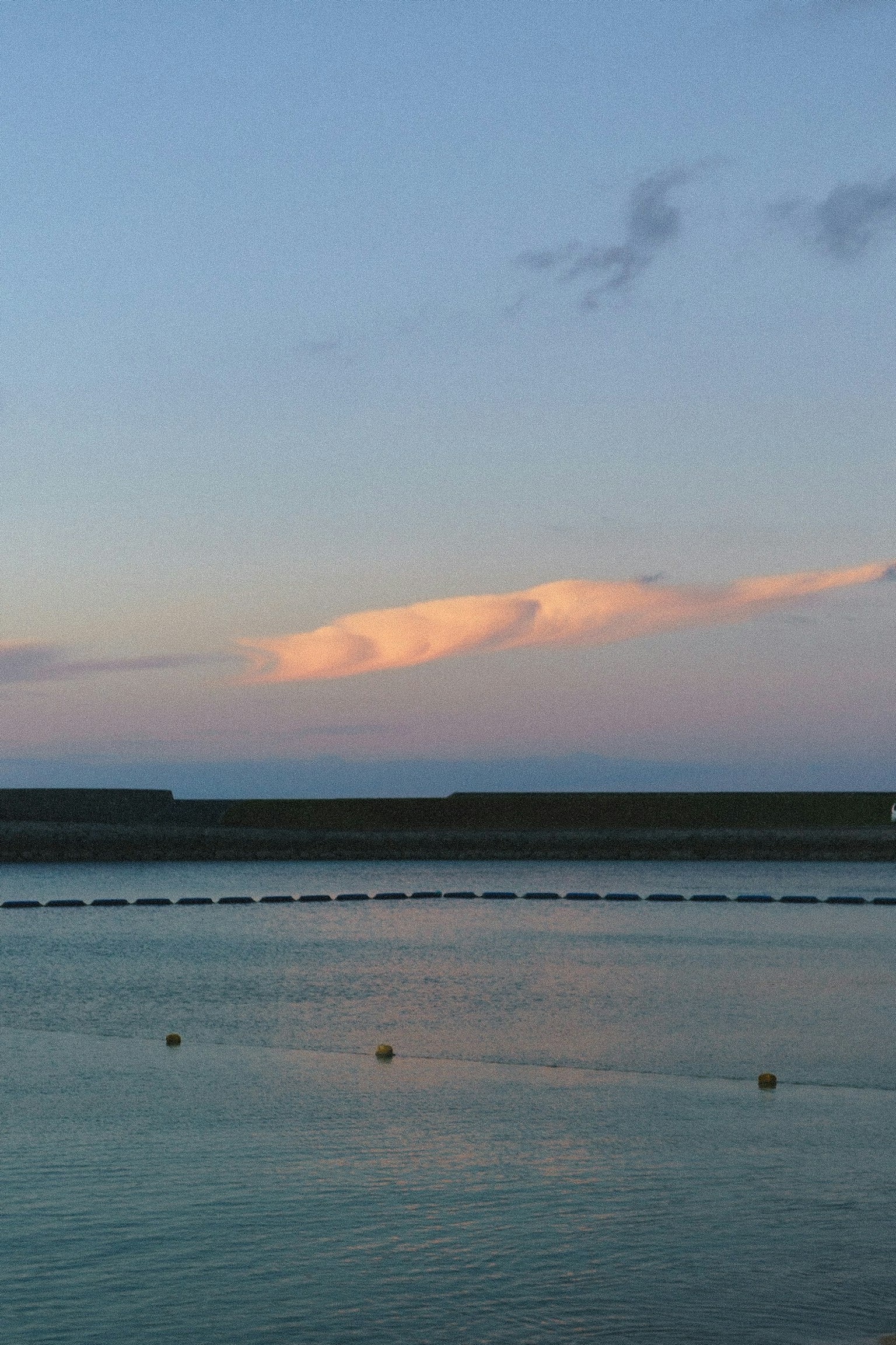 Superficie d'acqua tranquilla che riflette le nuvole al tramonto e vista sul mare calmo