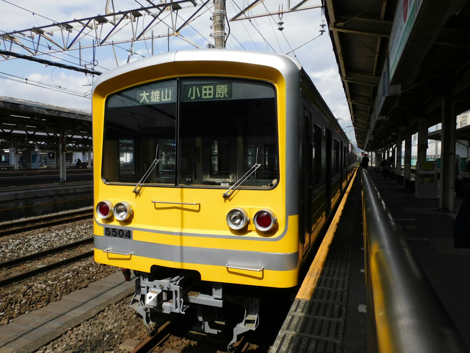 Un train jaune arrêté à une station sous un ciel dégagé