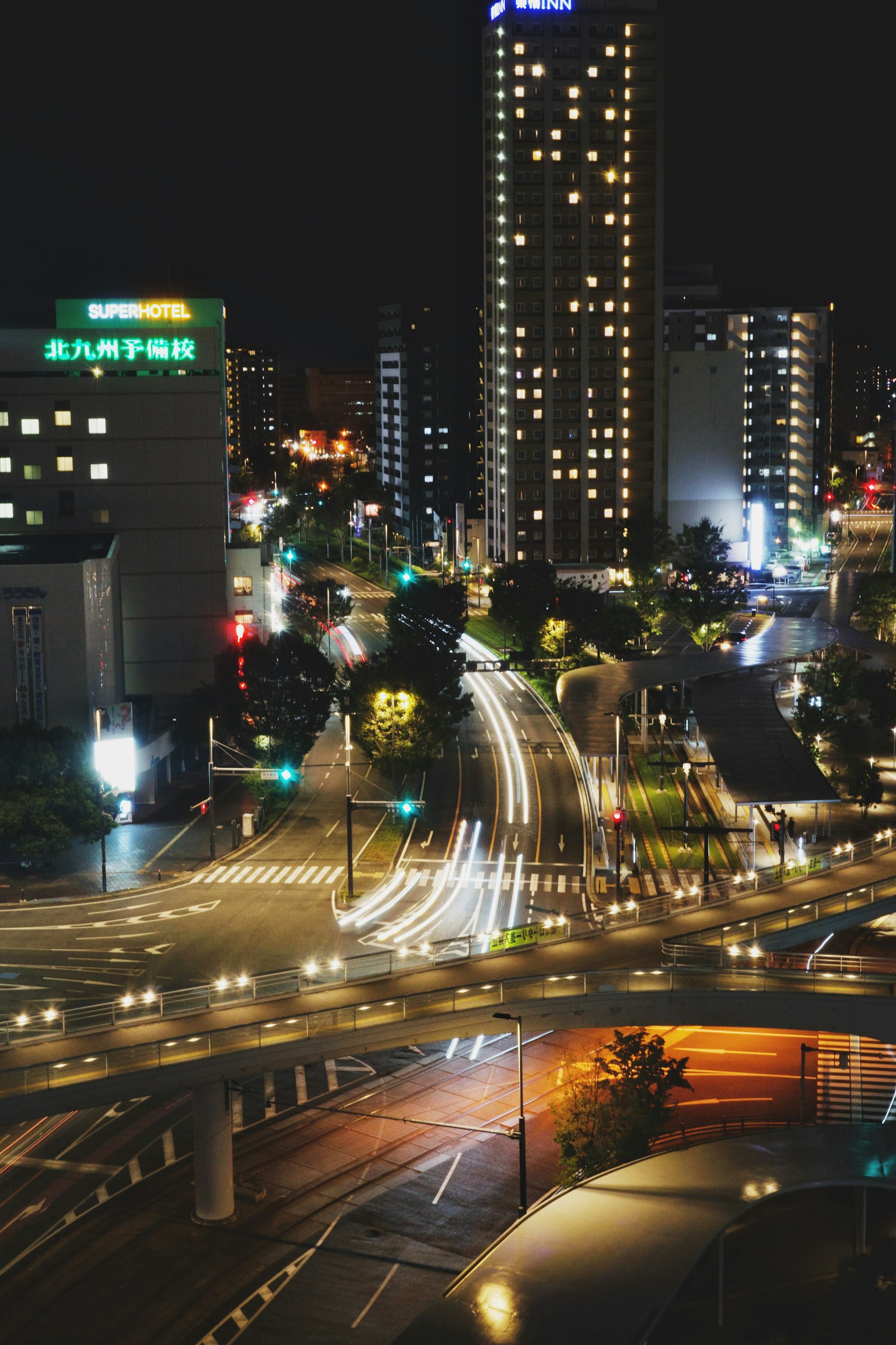 Intersección de la ciudad de noche con rascacielos iluminados y semáforos