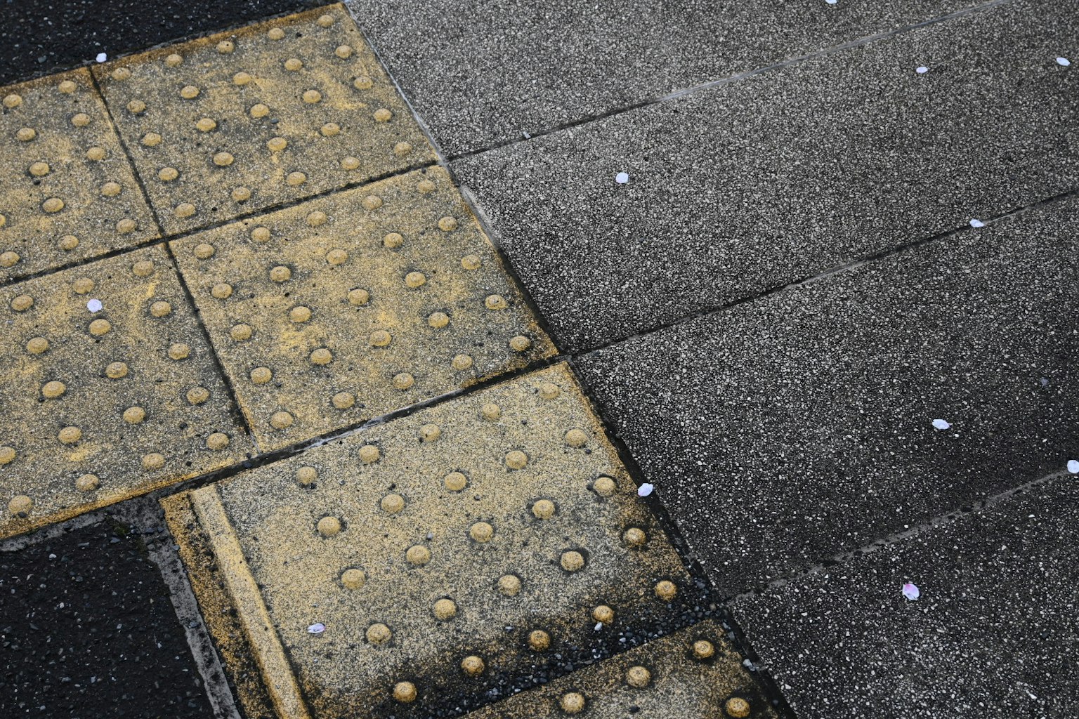 Sezione di un marciapiede pavimentato che mostra diverse texture e colori delle piastrelle
