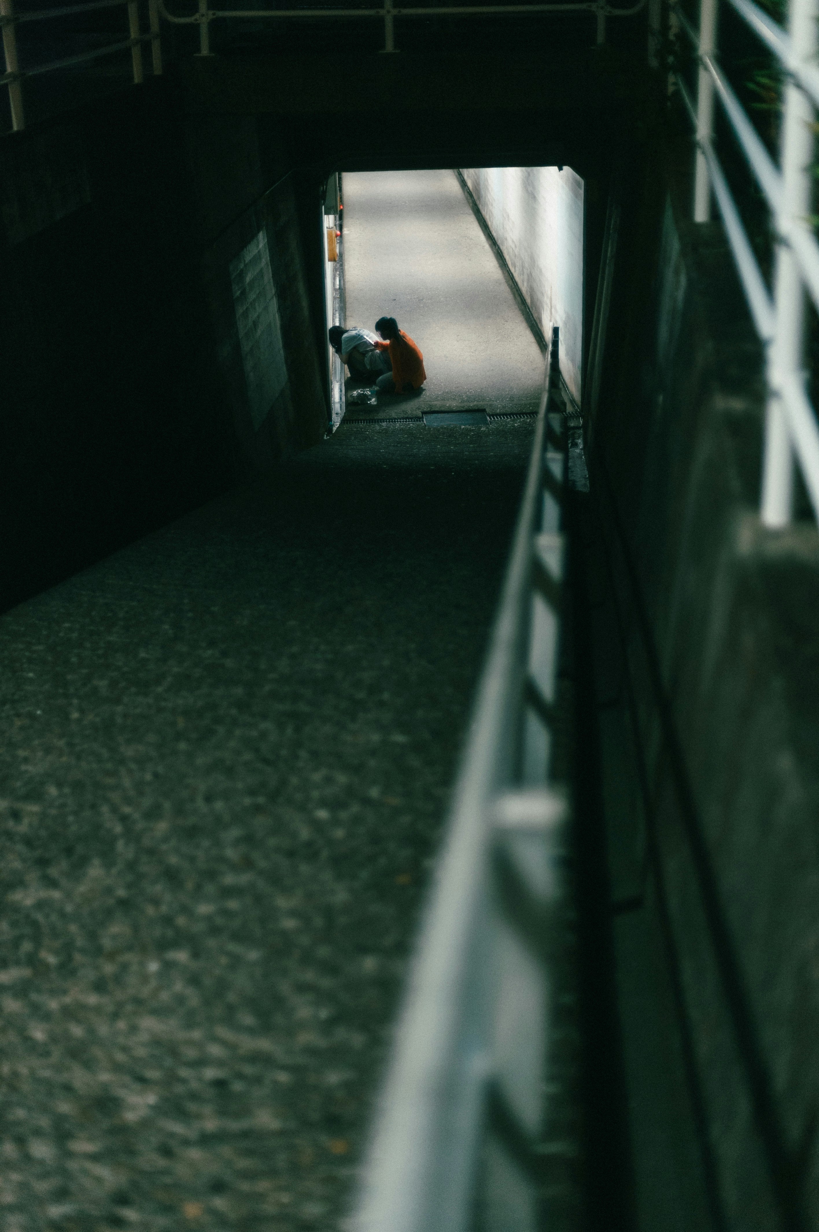 暗い通路の奥でしゃがむ人物