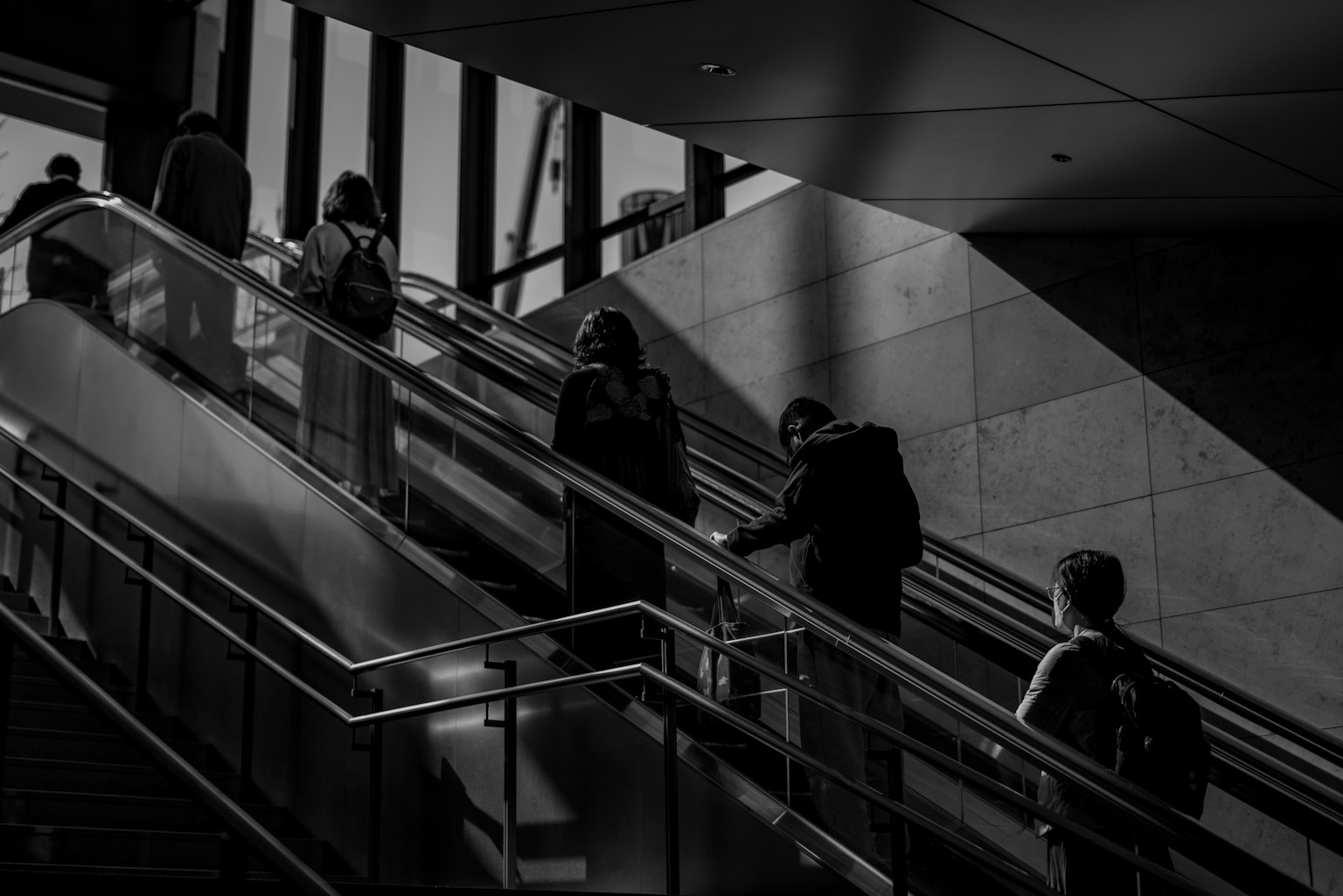 Silhouettes de personnes montant des escaliers avec un contraste de lumière