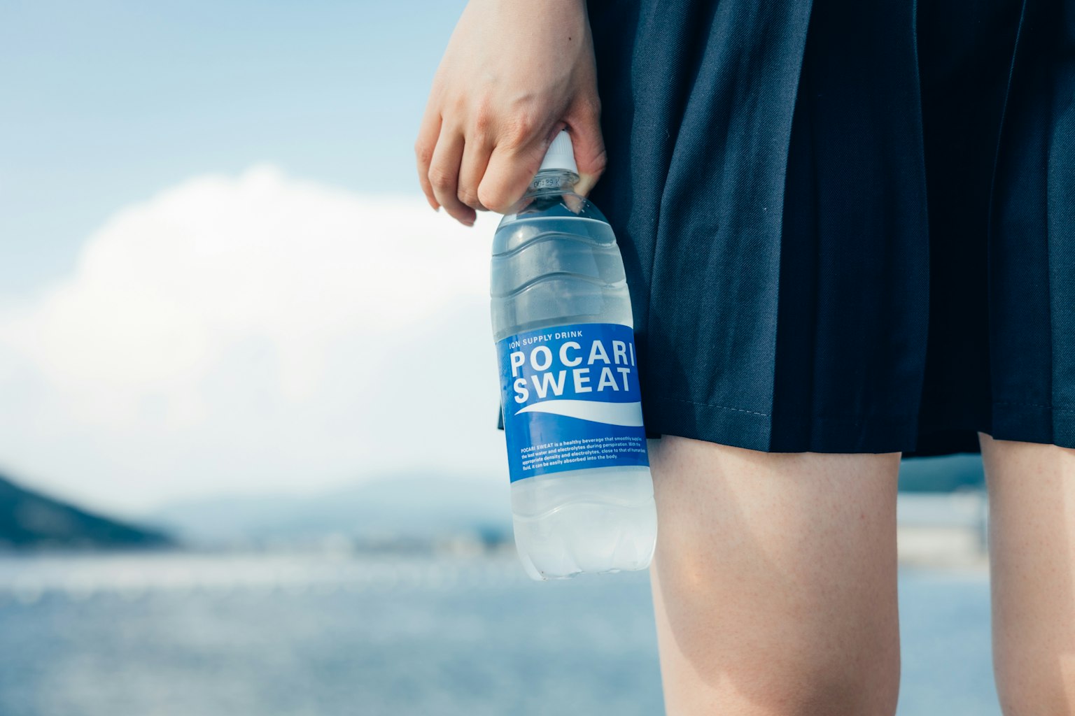 Femme tenant une bouteille de Pocari Sweat près de sa jambe