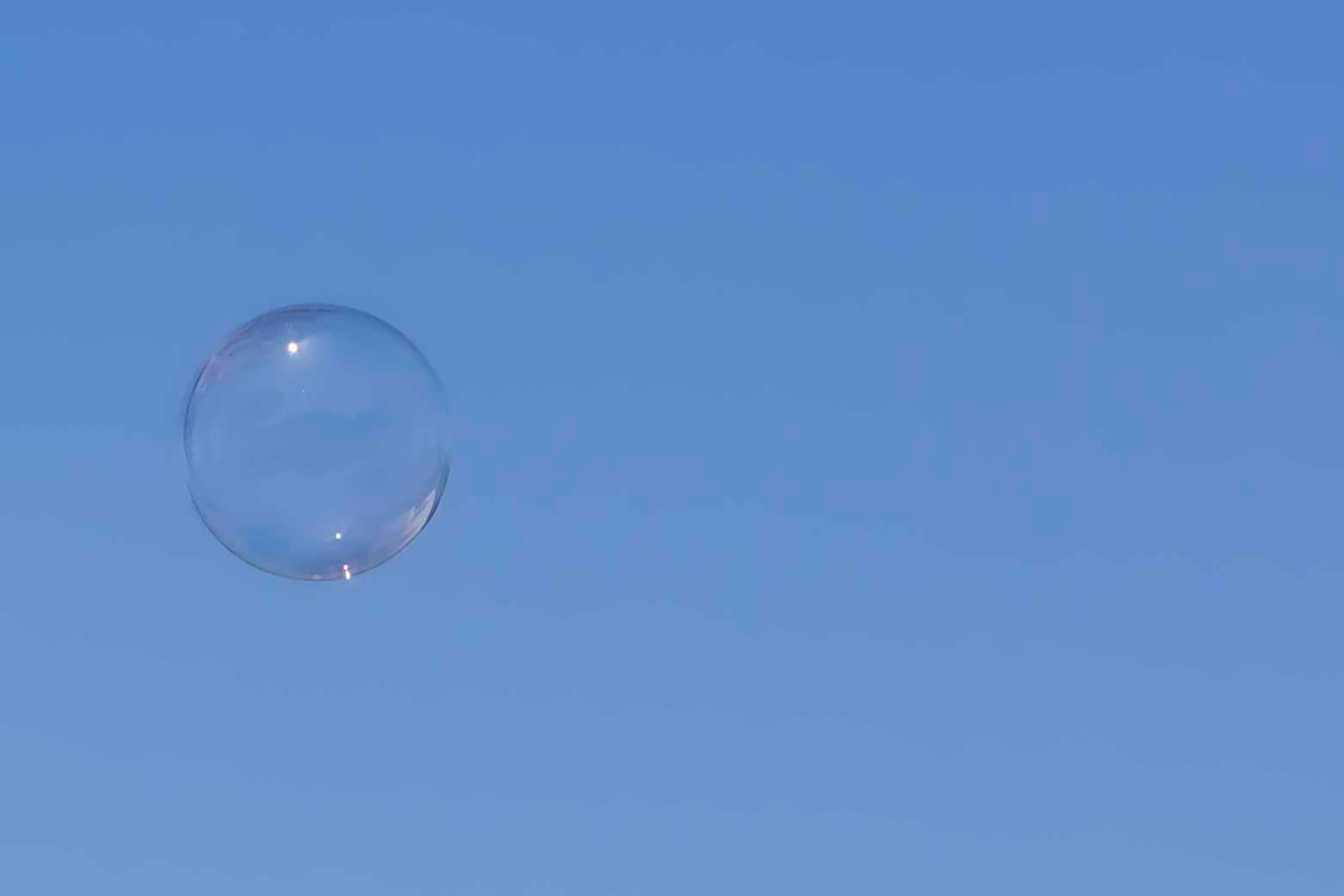 Eine transparente Seifenblase schwebt in einem blauen Himmel