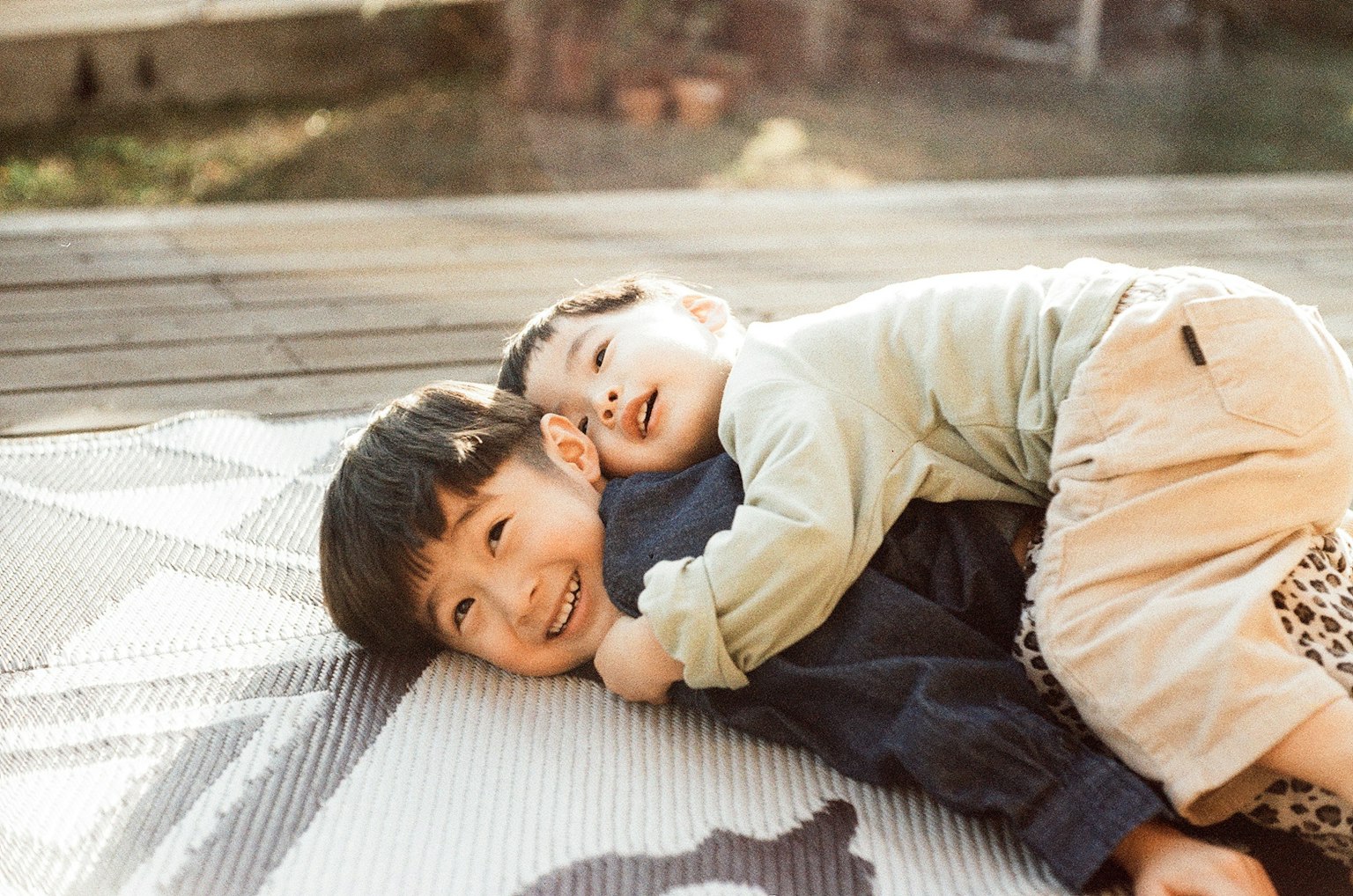Zwei Kinder spielen auf einer Matte im Freien