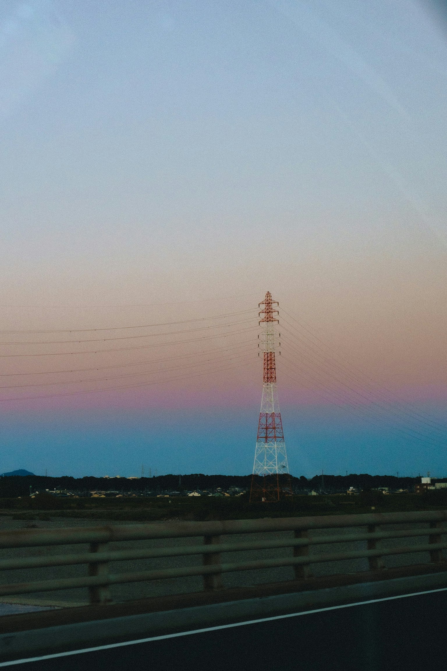 Tour de transmission contre un ciel au coucher du soleil et une route