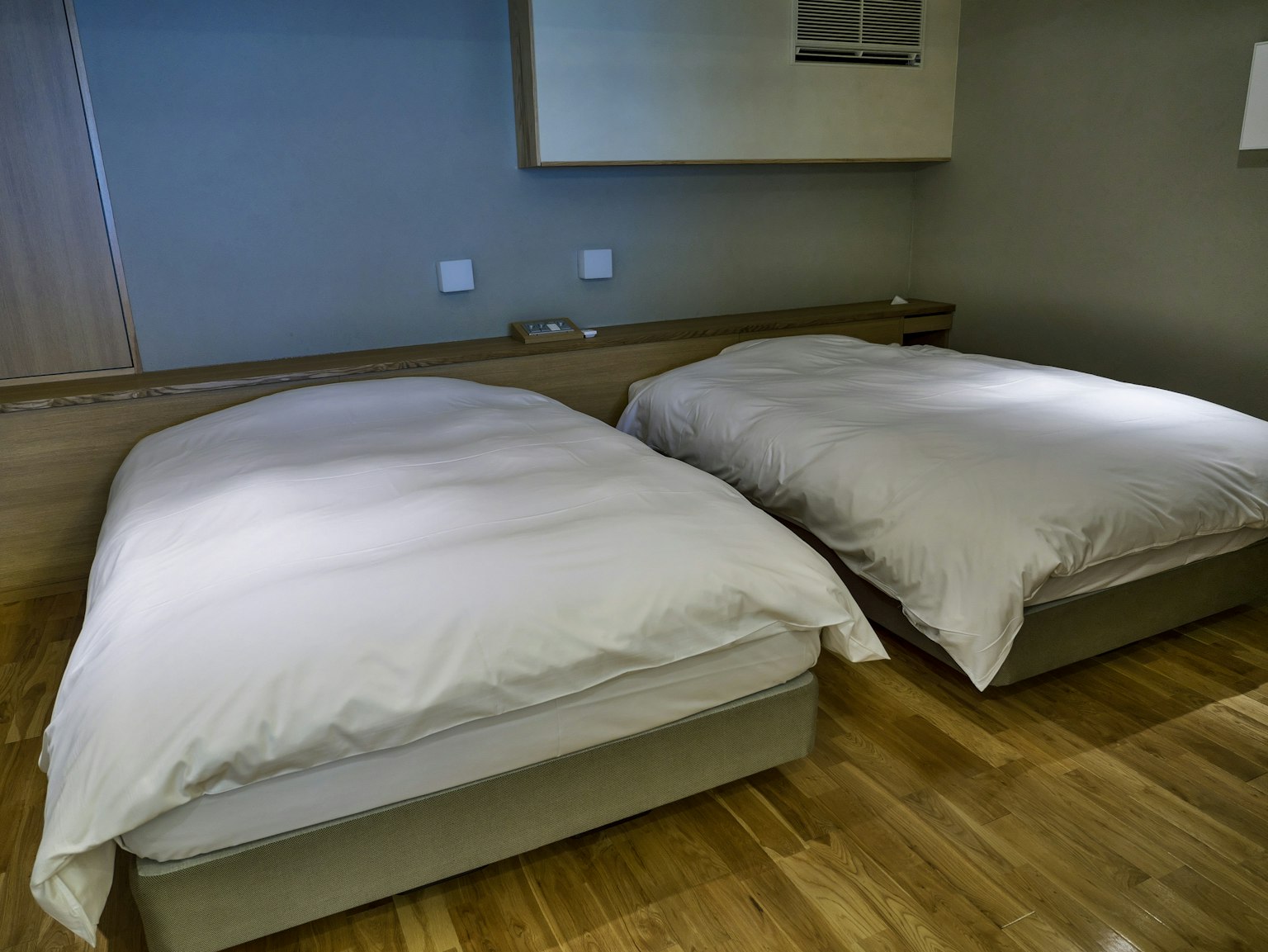 Một phòng hiện đại có hai chiếc giường đơn giản với ga trải giường trắng