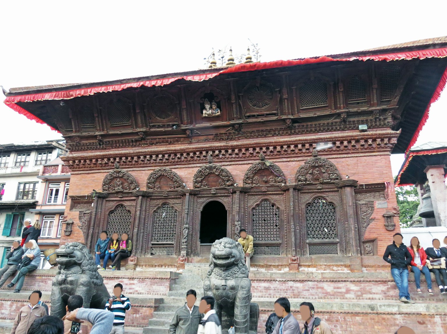 Architecture de temple népalais traditionnel avec des fenêtres en bois finement sculptées et des statues de lions à l'entrée