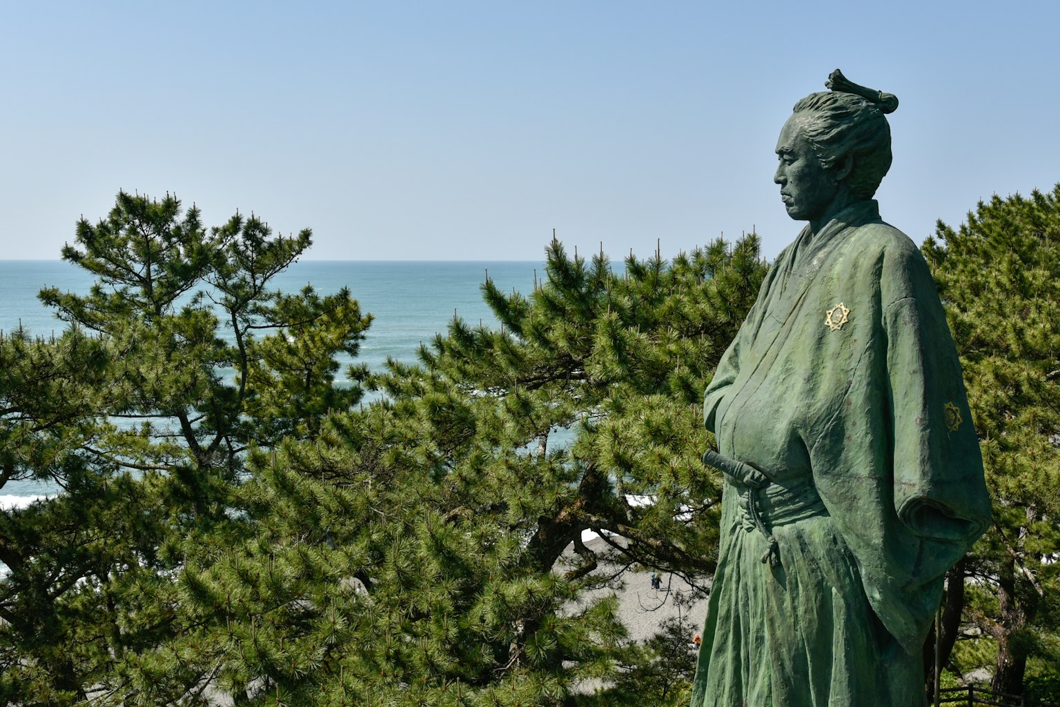 Eine grüne Statue steht mit dem Ozean im Hintergrund