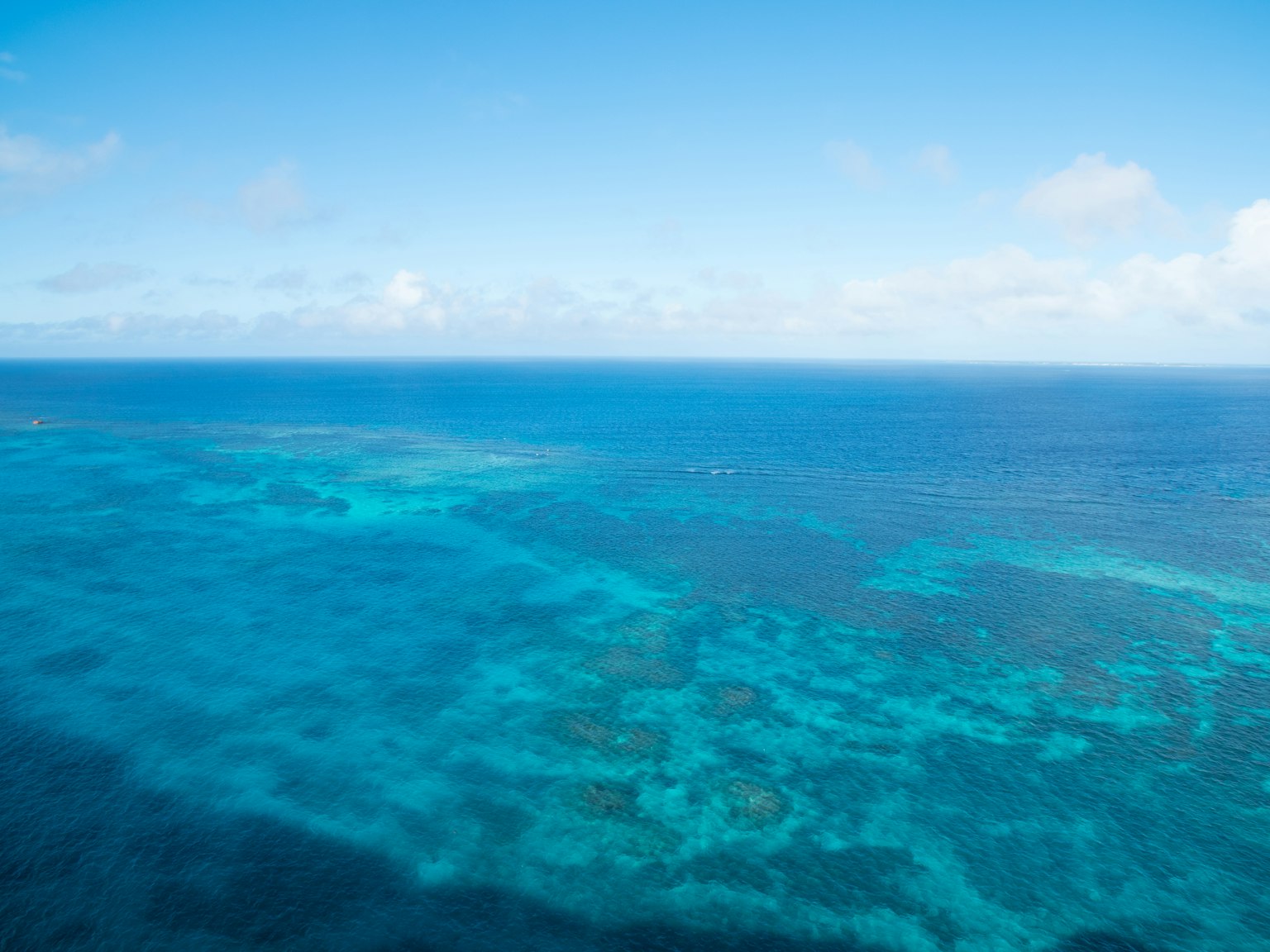 Vast blue ocean under a bright sky with clear turquoise waters and coral reefs
