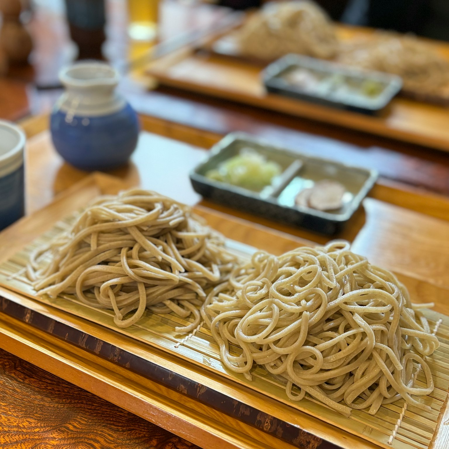 A photo of Japanese soba noodles served in two portions on a bamboo tray