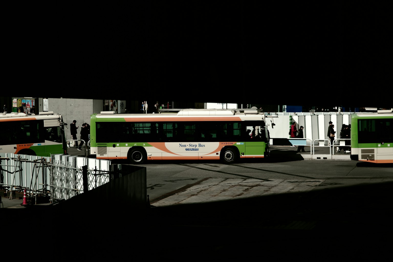 Buses at a transportation hub with green and orange colors